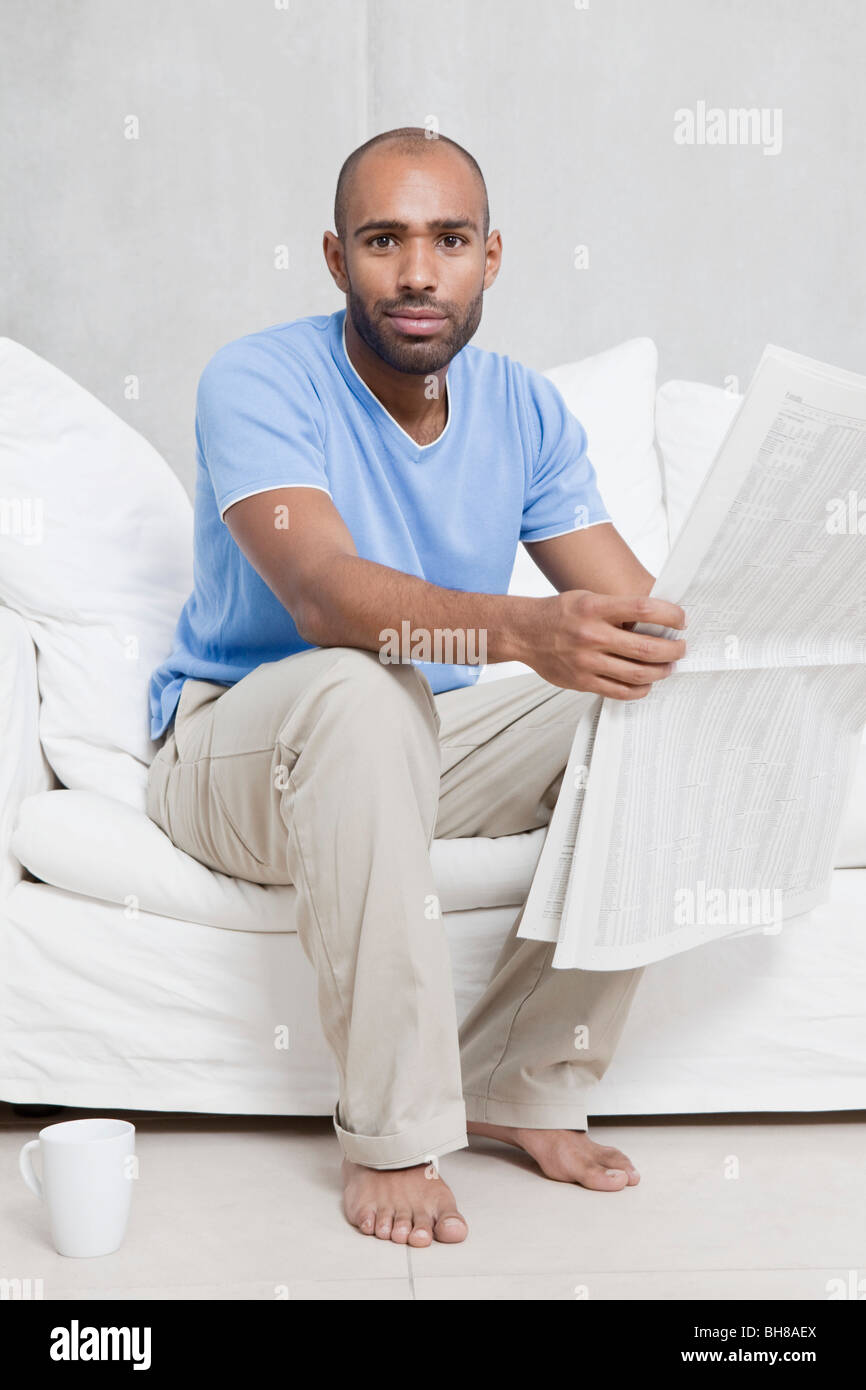 Ein Mann sitzt auf einem Sofa mit einer Zeitung Stockfoto