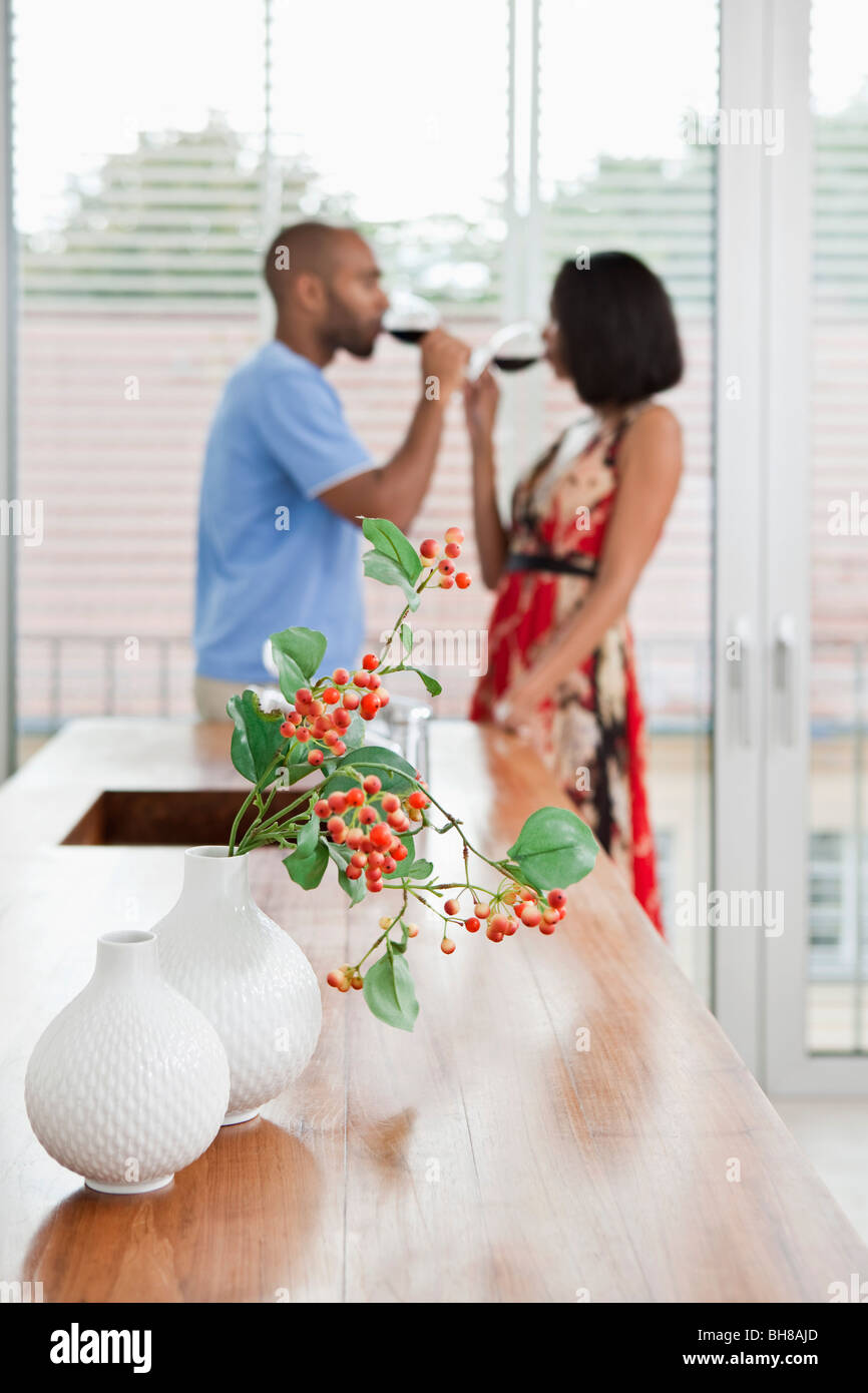Zwei Vasen, Beeren mit einem Zweig der Hypericum drin, junges Paar im Hintergrund Stockfoto