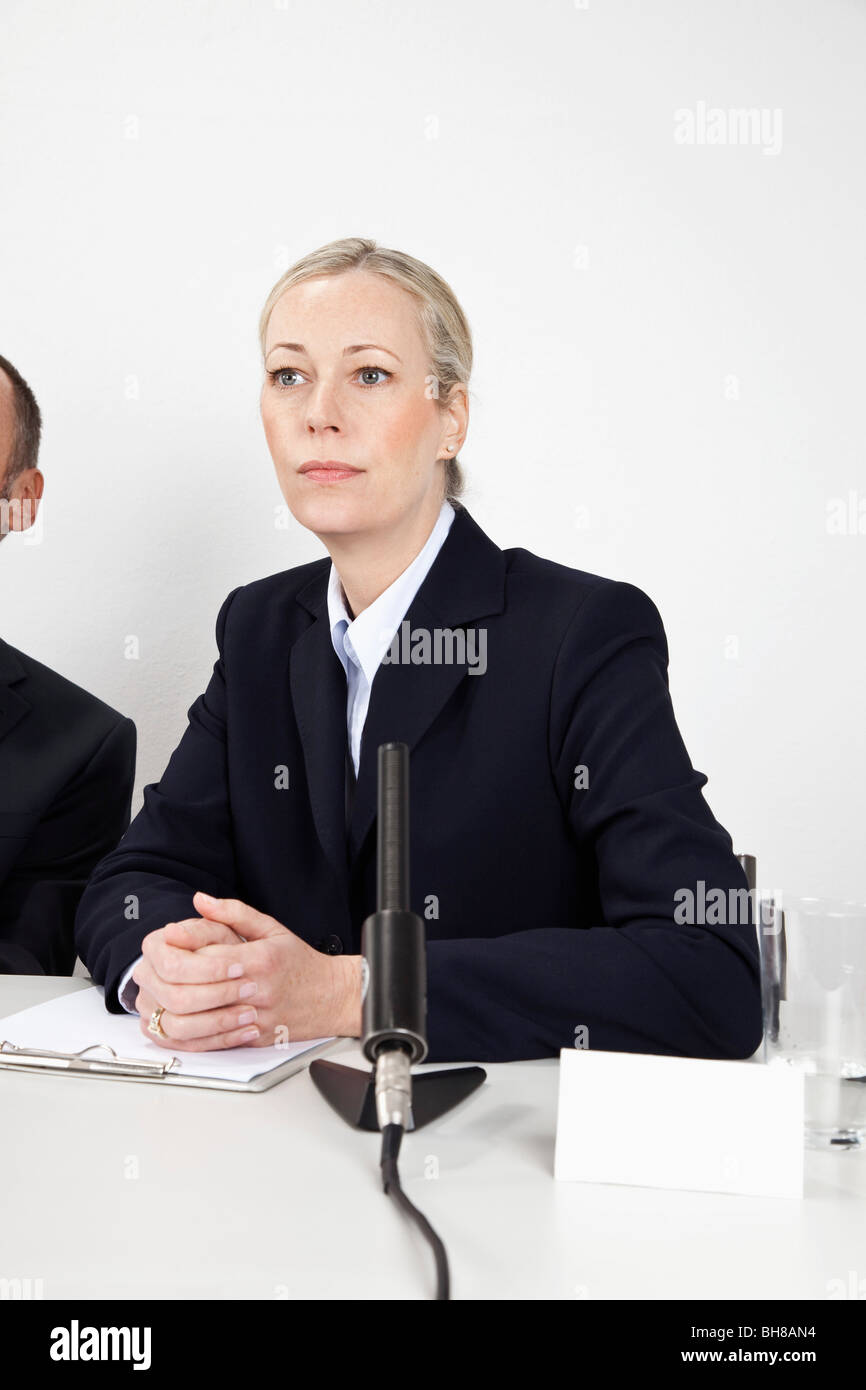 Eine Frau sitzt an einem Schreibtisch mit einem Mikrofon Stockfoto