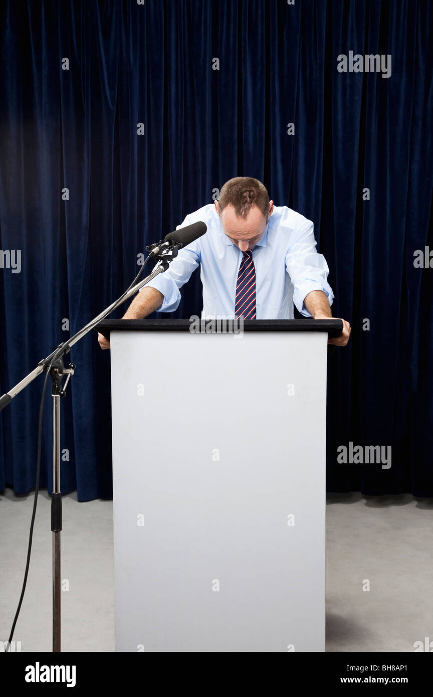 Ein Mann schaut hinter einem Rednerpult Stockfoto