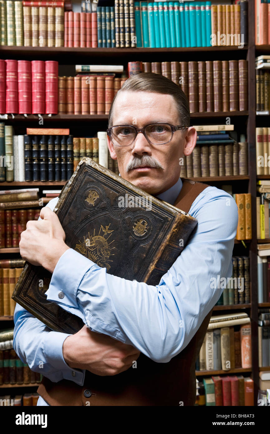 Ein Mann ein Buch hält fest an seine Brust und auf der Suche nach verdächtigen in einer Buchhandlung Stockfoto