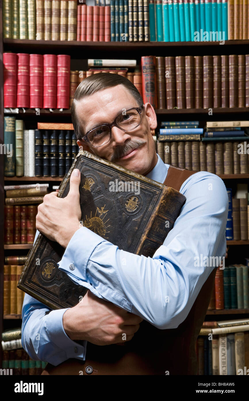 Ein Mann hält ein Buch fest an seine Brust glücklich in einer Buchhandlung Stockfoto