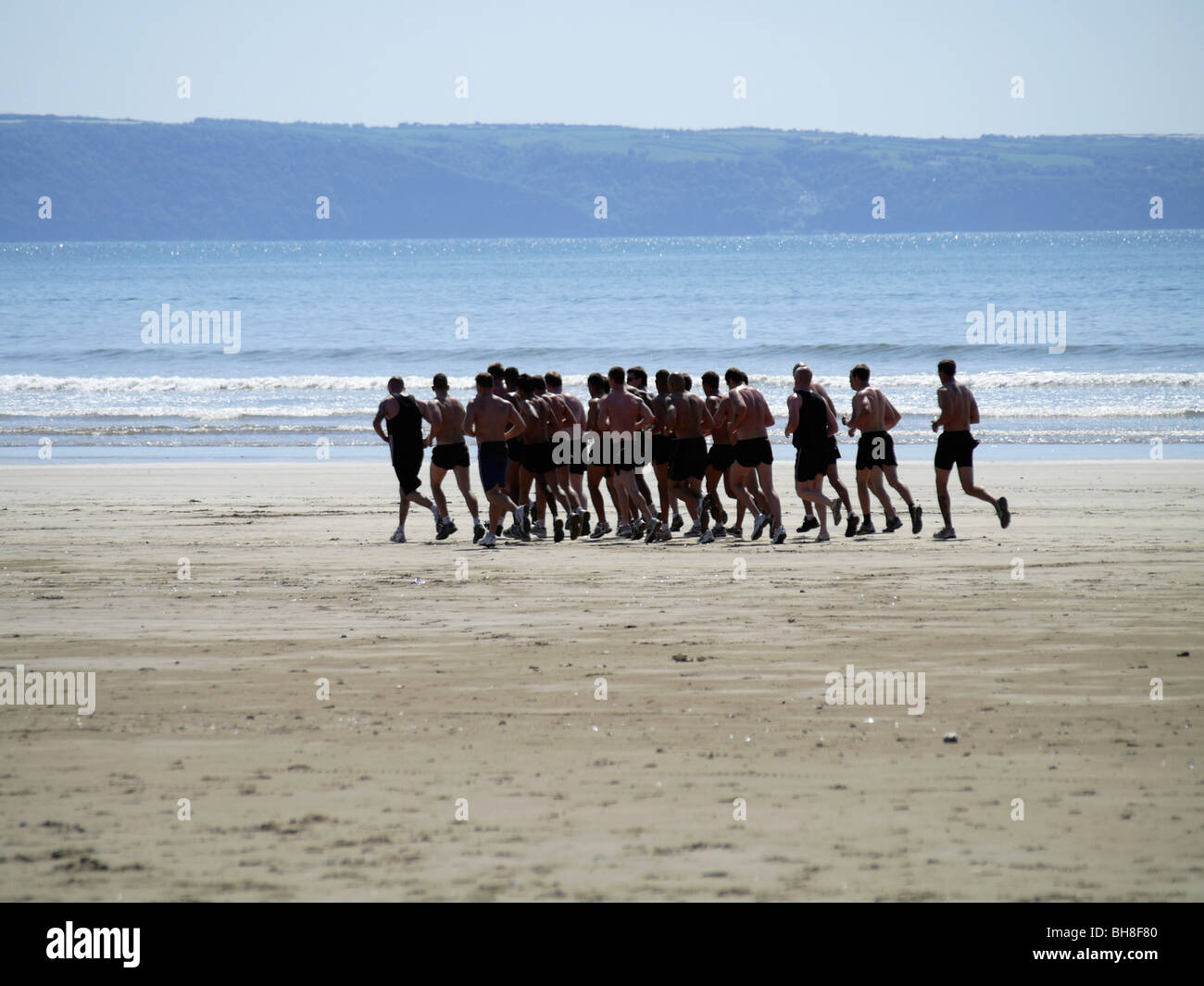 bewaffneten Service-Personal in einer Mannschaft an einem Strand entlang laufen Stockfoto