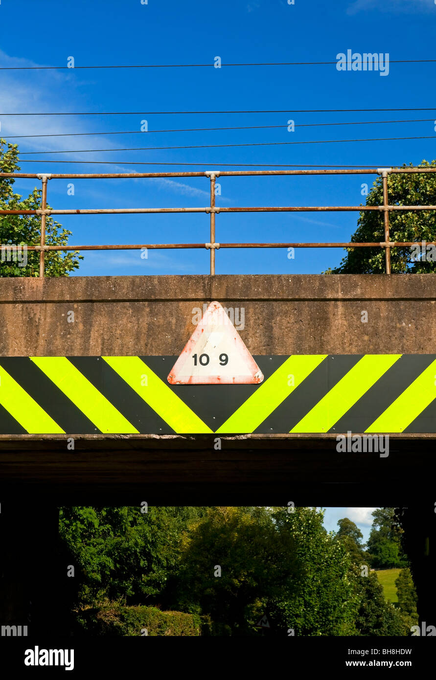Niedrigen Eisenbahnbrücke mit Warnzeichen für Fahrer von hohen Fahrzeugen in Cumbria, England UK Stockfoto