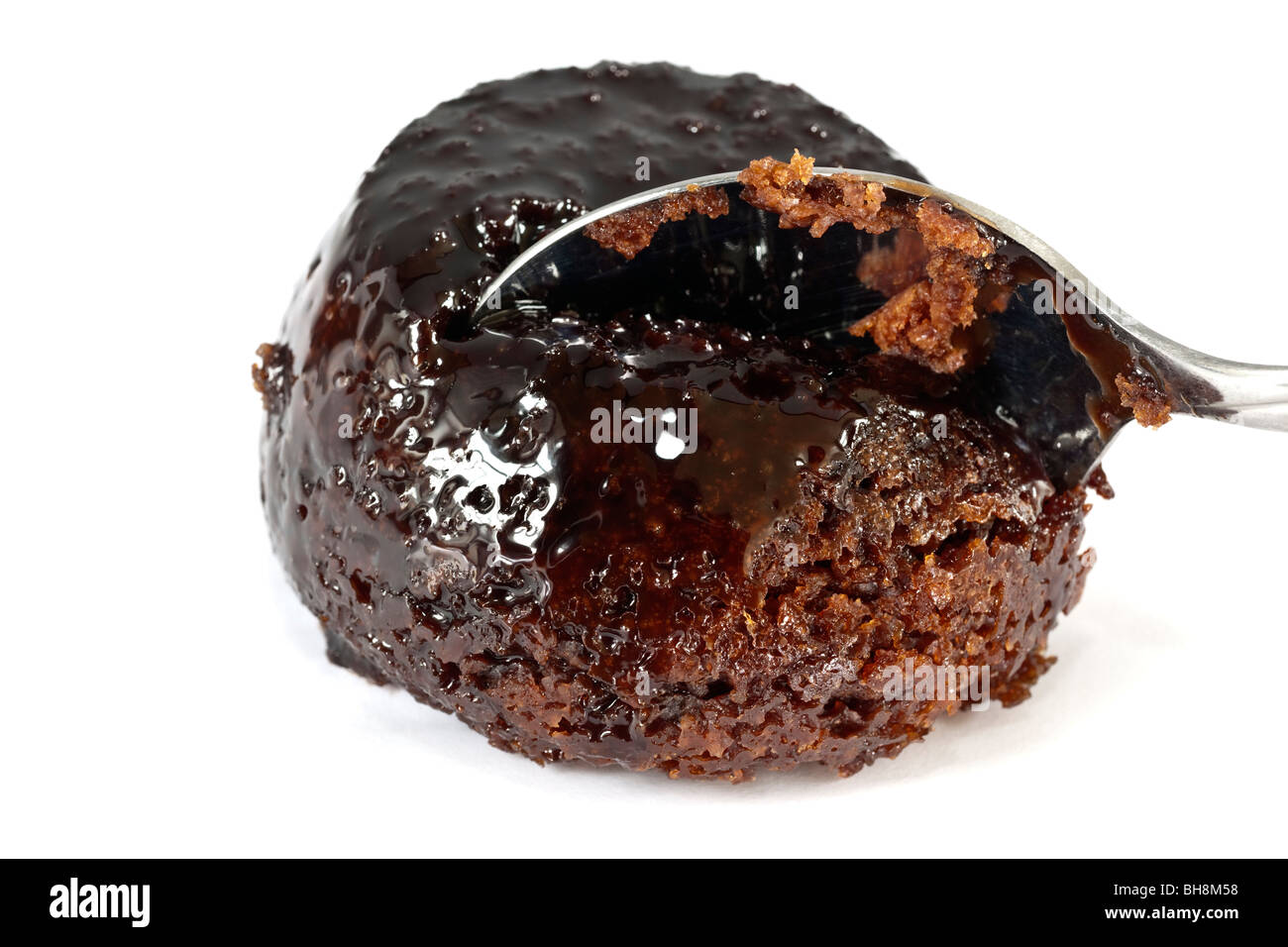 Ein Dessert-Löffel schneiden einen Teil des kleinen Schokolade Schwamm Pudding mit Soße Stockfoto
