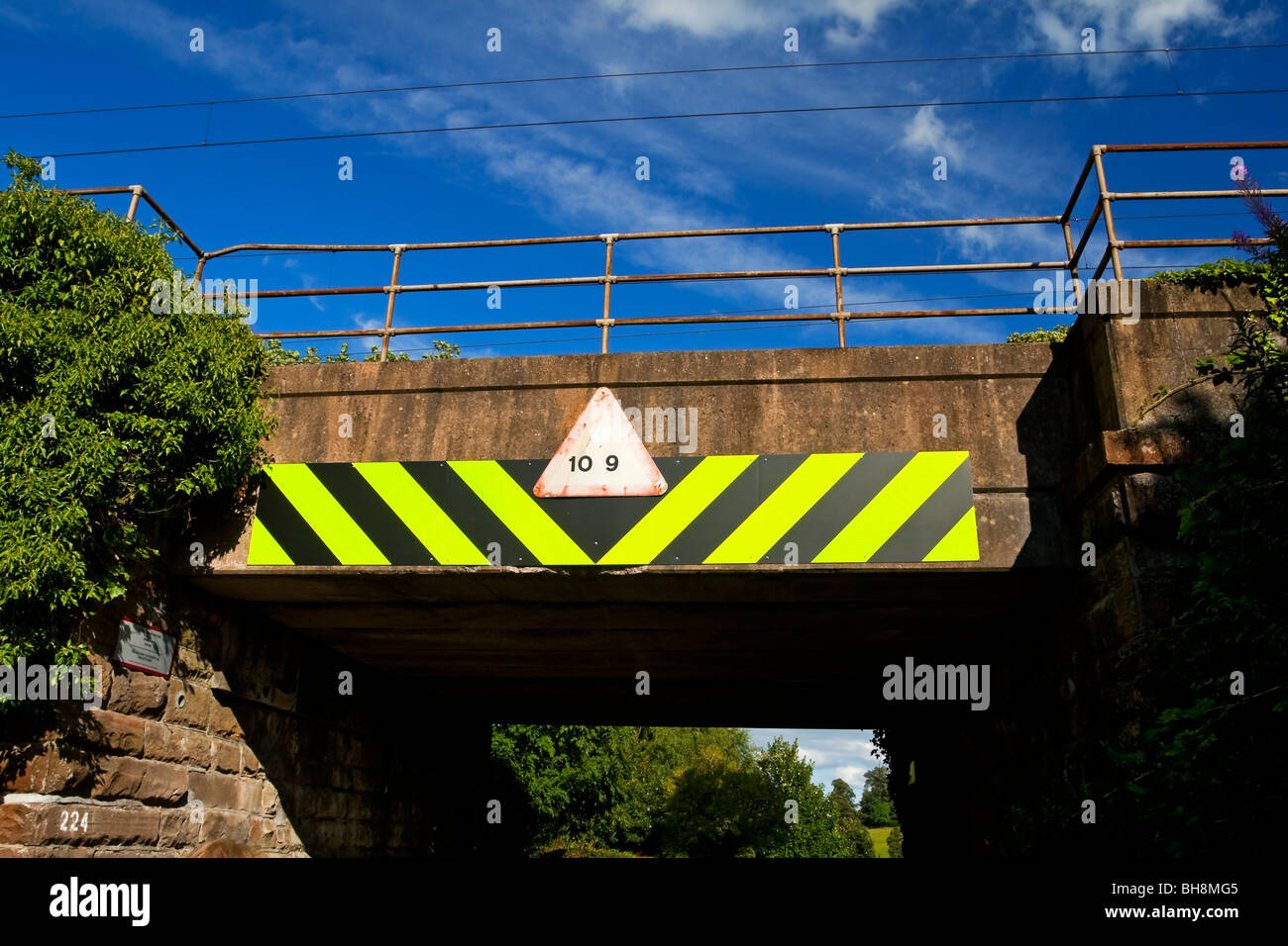 Niedrigen Eisenbahnbrücke mit Warnzeichen für Fahrer von hohen Fahrzeugen in Cumbria, England UK Stockfoto
