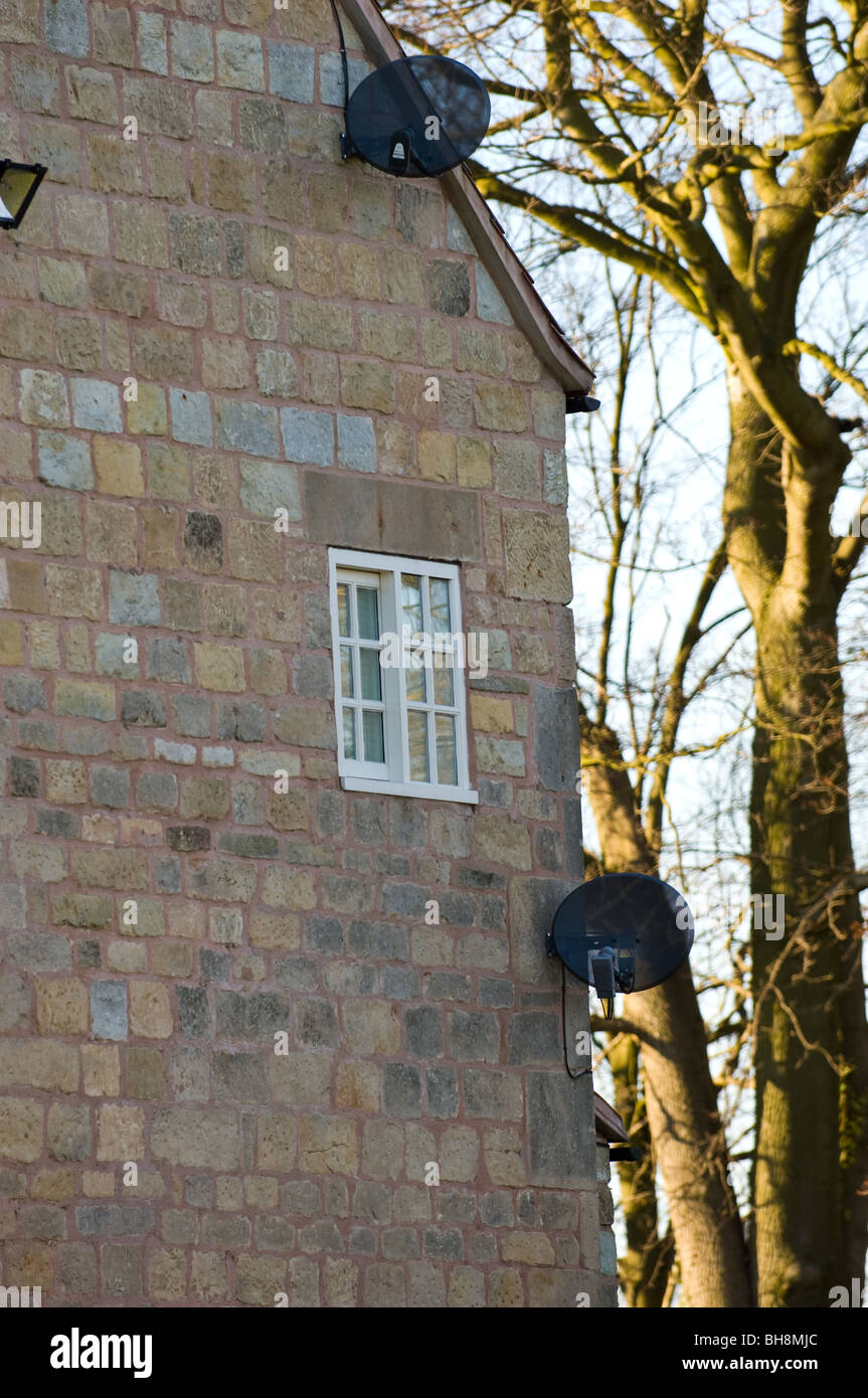 Satellitenschüsseln montiert an der Wand eines traditionellen Stein Hof Haus gebaut. Stockfoto