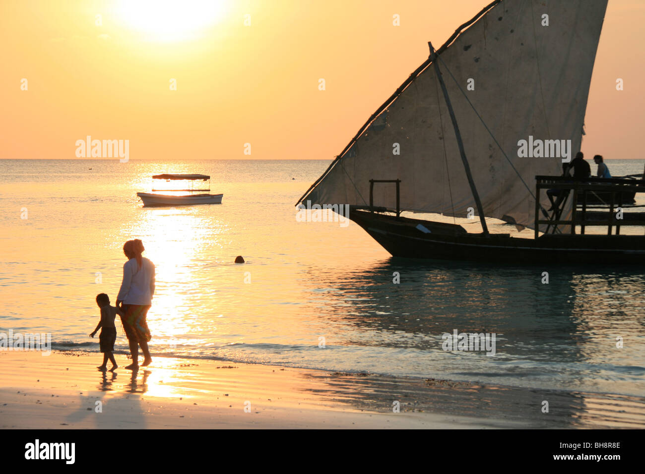 ein Strand Sonnenuntergang auf Sansibar mit Dhow Segeln Boot die Touristen für eine Bootsfahrt bei Sonnenuntergang Stockfoto