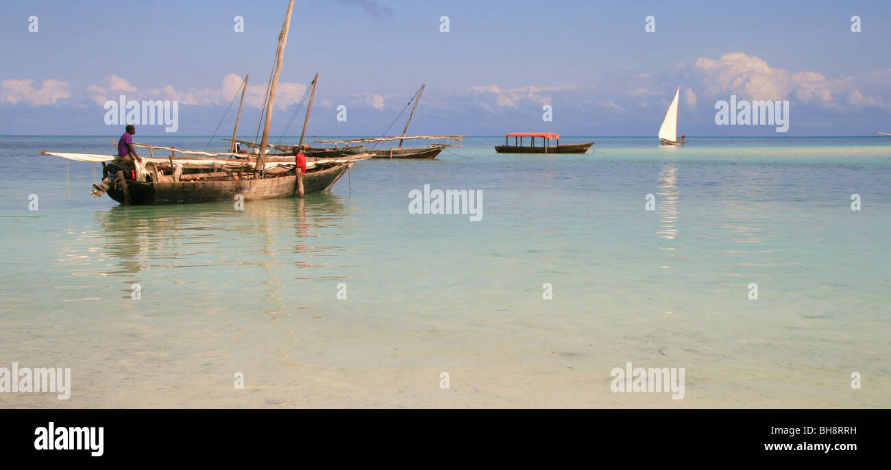 hölzerne Segelboote vor Nungwi Beach in Sansibar, die weißen Segel von einer Dhau am Horizont in See stechen wird vorbereitet Stockfoto