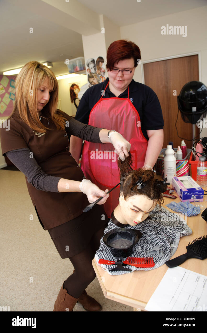 Eine Frau berufliche Tutor Lehre Friseur Fähigkeiten für Mädchen im Teenageralter in der Sekundarschule, UK Stockfoto