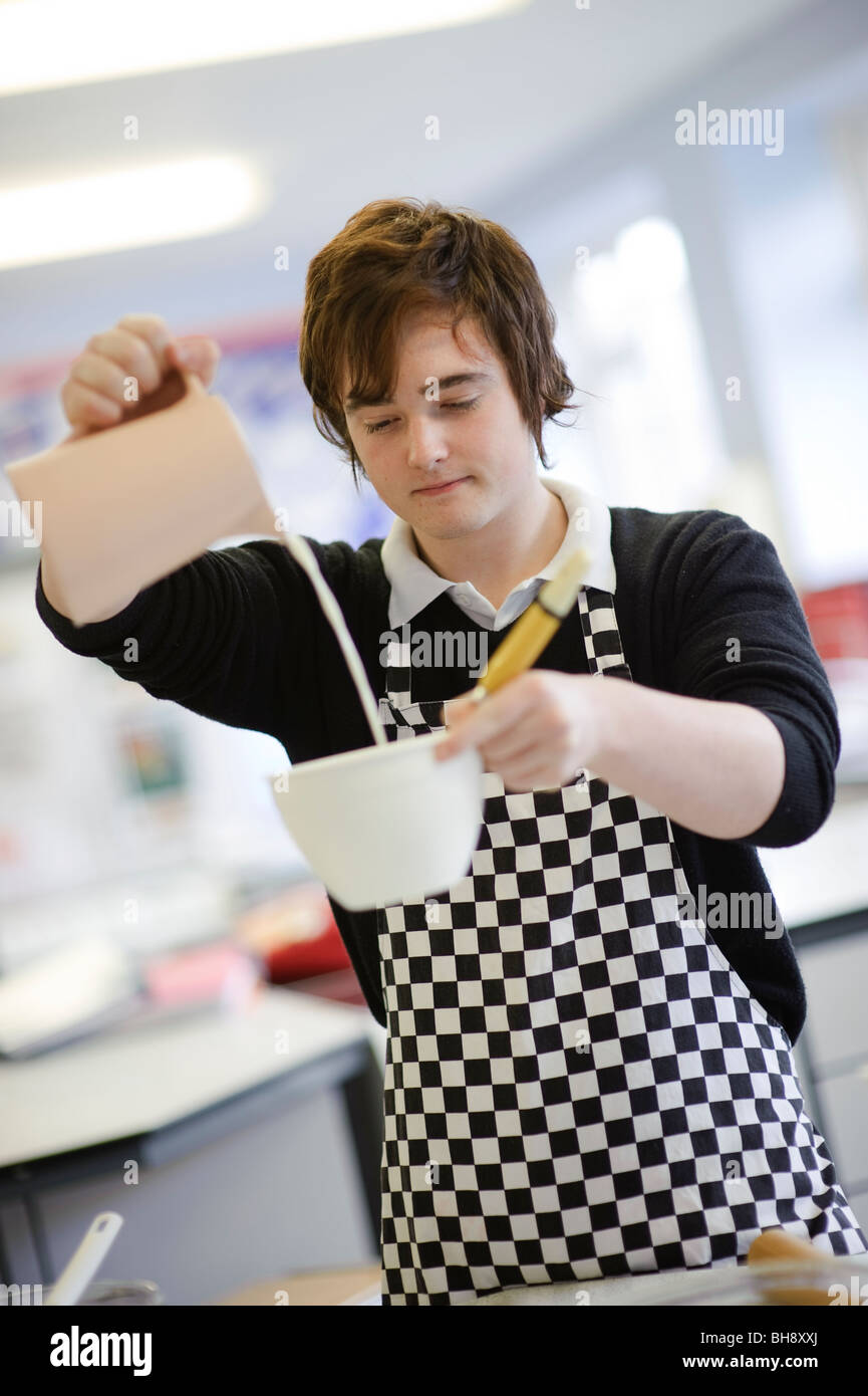 Teenager Zutaten Mess- und gießt Milch in einer Schüssel in Essen-Wissenschaft-Kochkurs, Secondary School UK Stockfoto
