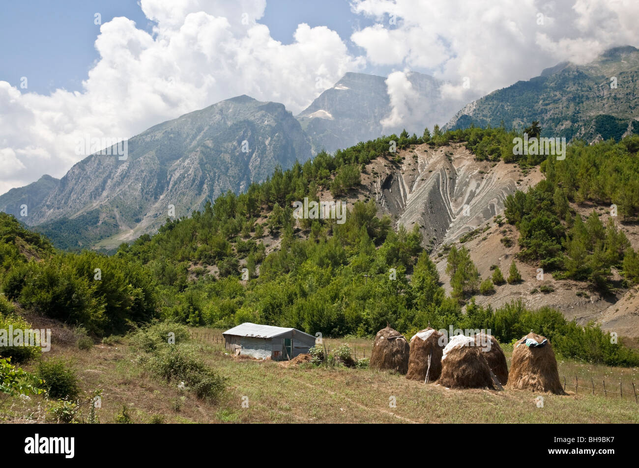 Heuhaufen im Vjoses-Tal mit den Nemercke-Bergen im Hintergrund, in der Nähe von Permet im Süden Albaniens Stockfoto