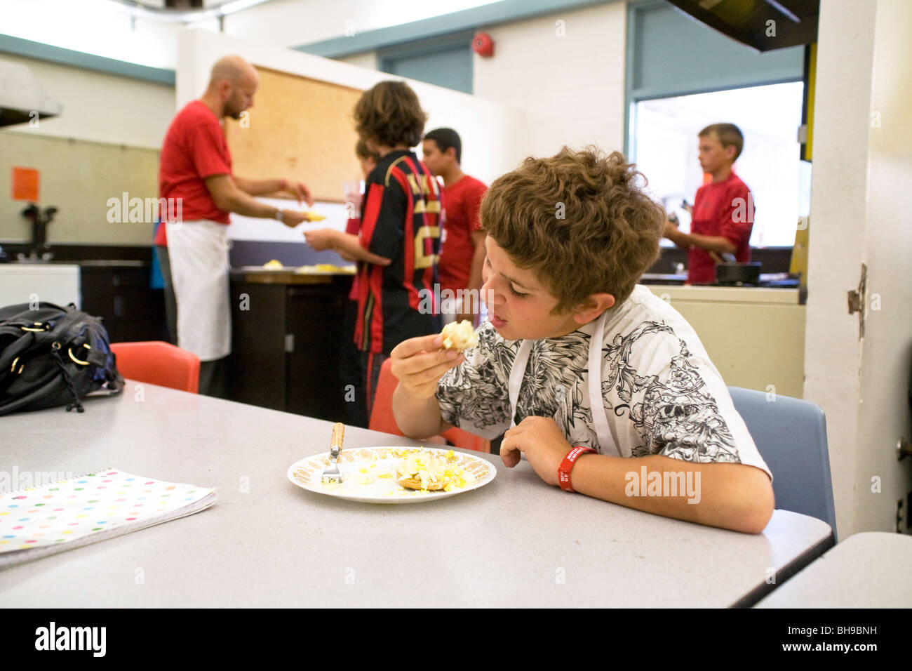 Ein Junge an einer Mittelschule in Südkalifornien isst einen getoasteten Bagel nach nach dem Kochen es in Hauswirtschaft Klasse. Stockfoto