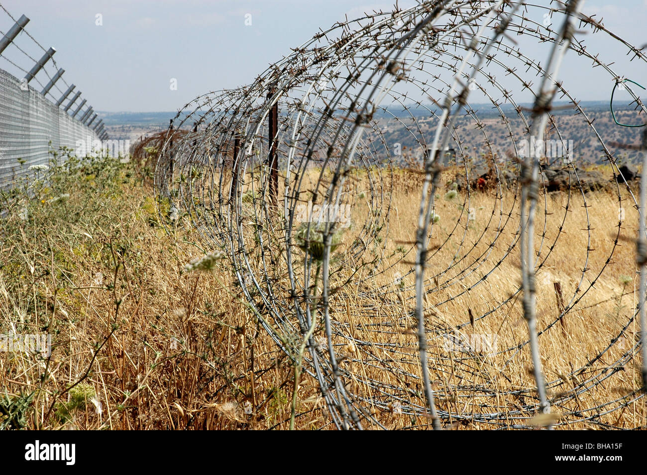 Ein Stacheldraht-Coil-Zaun, der die Grenze zwischen dem Yarmouk-Tal in Jordanien und den besetzten Golanhöhen in Israel im Nahen Osten abgrenzt. Stockfoto