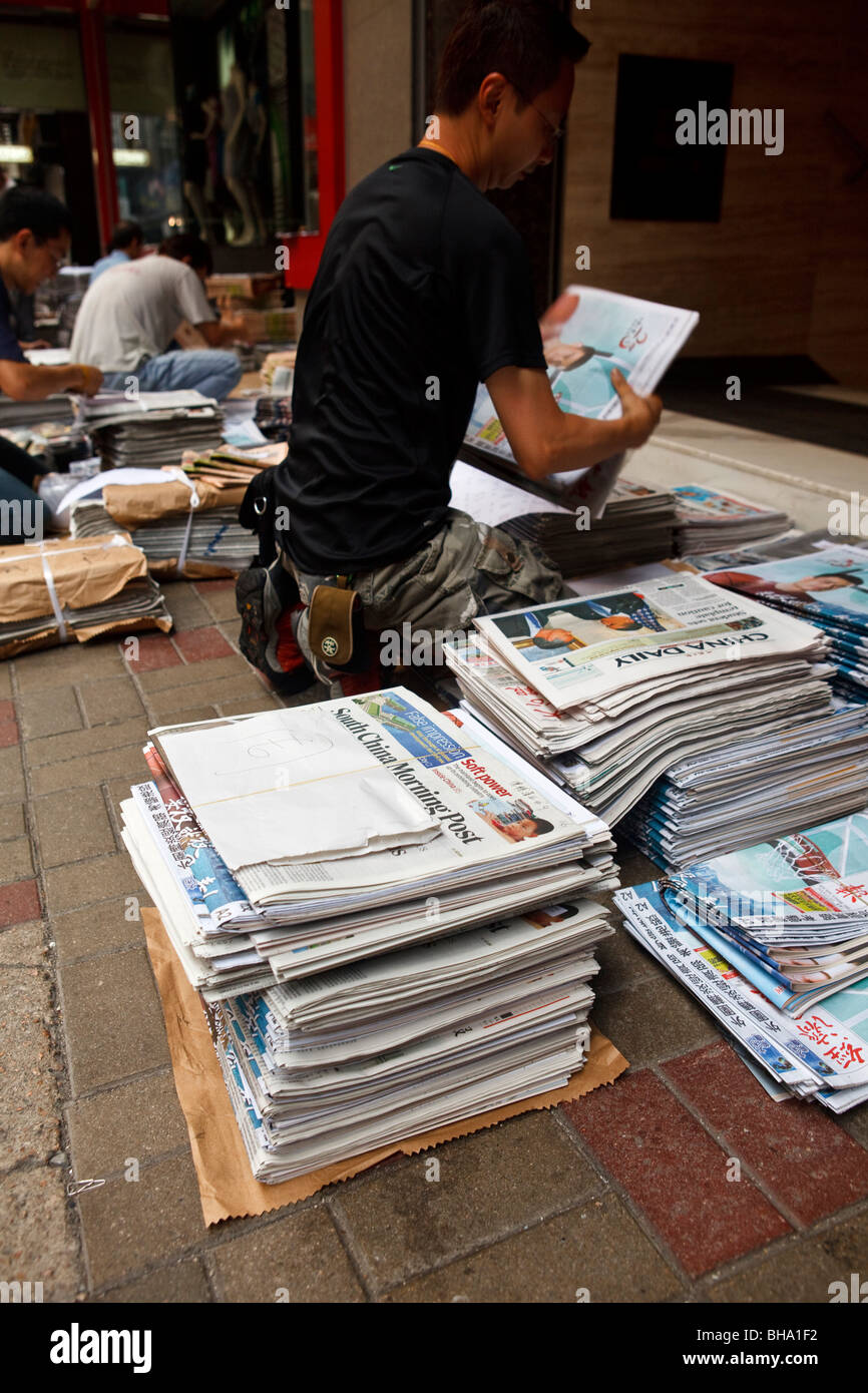 Ein Mann-Stacks und Packungen Zeitungen als Bestandteil der Lieferung und Vertrieb von Zeitungen in Hongkong. Stockfoto