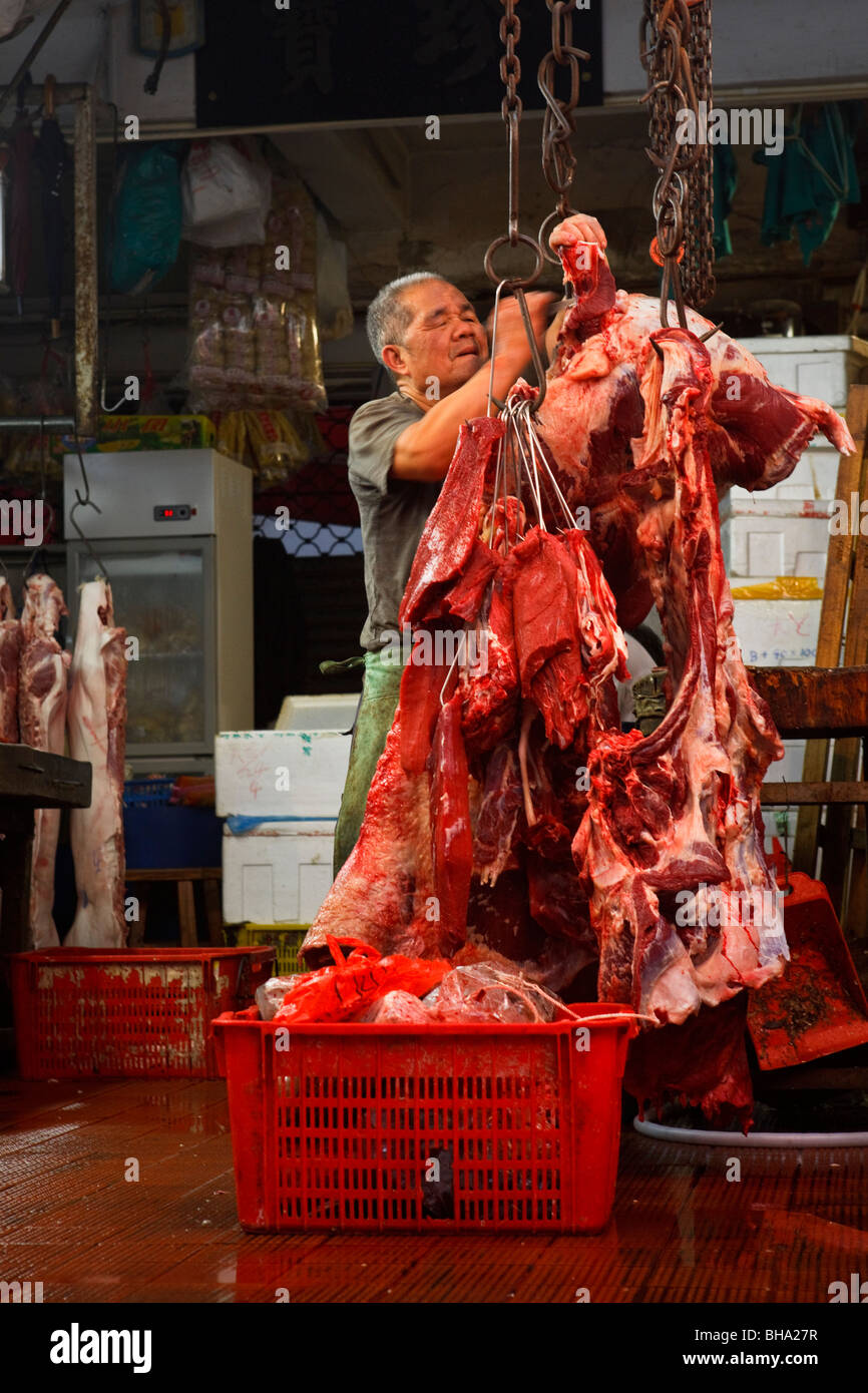 Ein Metzger auf Bowrington Road Strassenmarkt Gemüsemesser und Vorbereitung schneidet ein Rindfleisch-Kadaver in Hong Kong. Stockfoto