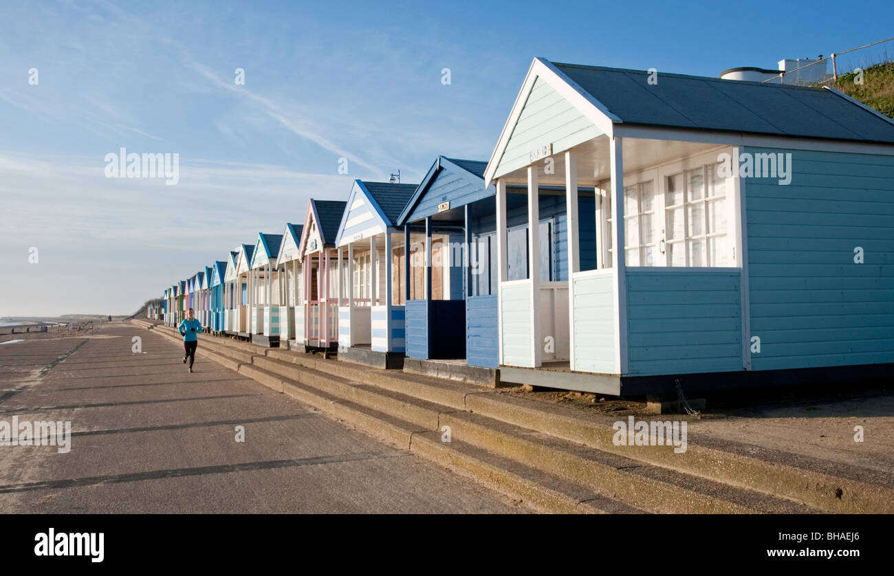 Die Strandpromenade mit hölzernen Strandhütten und Frau Jogger, Southwold Suffolk England UK Stockfoto