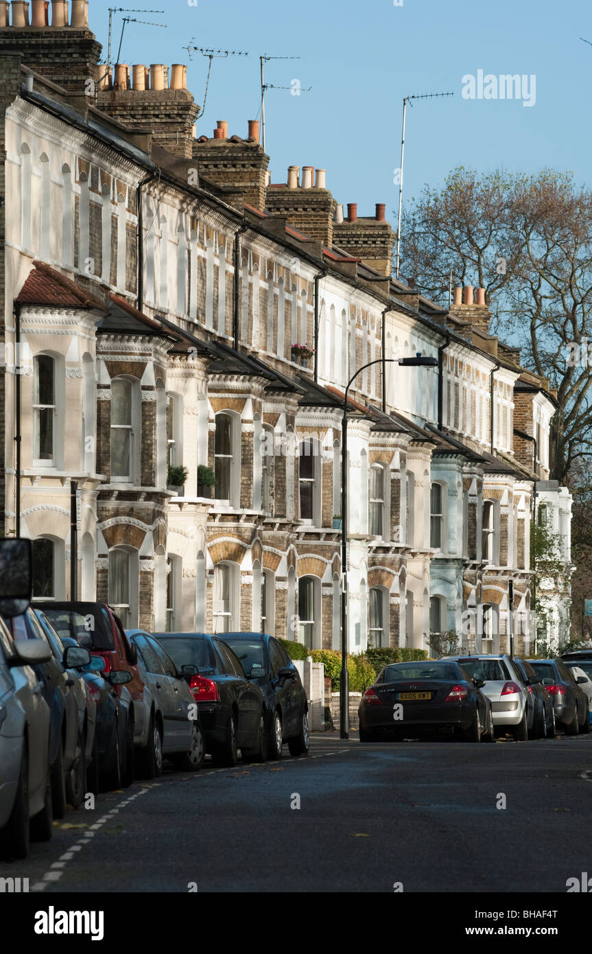 dicht geparkten Autos und viktorianischen Reihenhäusern, einem typischen Londoner Straßenszene Stockfoto