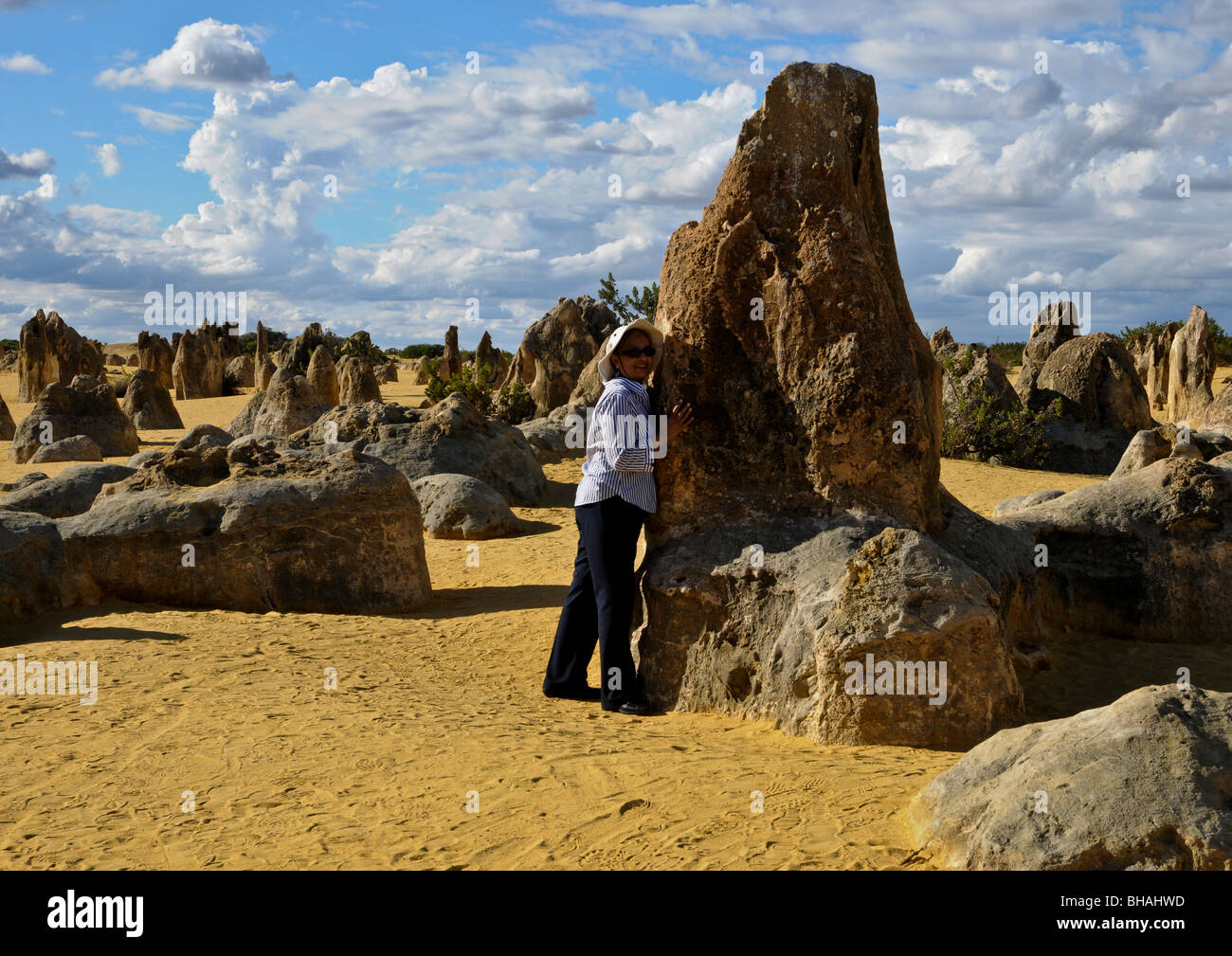 Weibliche umarmen große stehende Stein ähnlich menschliche Figur unter den übrigen Formen auf Pinnacles Nationalparks Western Australia. Stockfoto