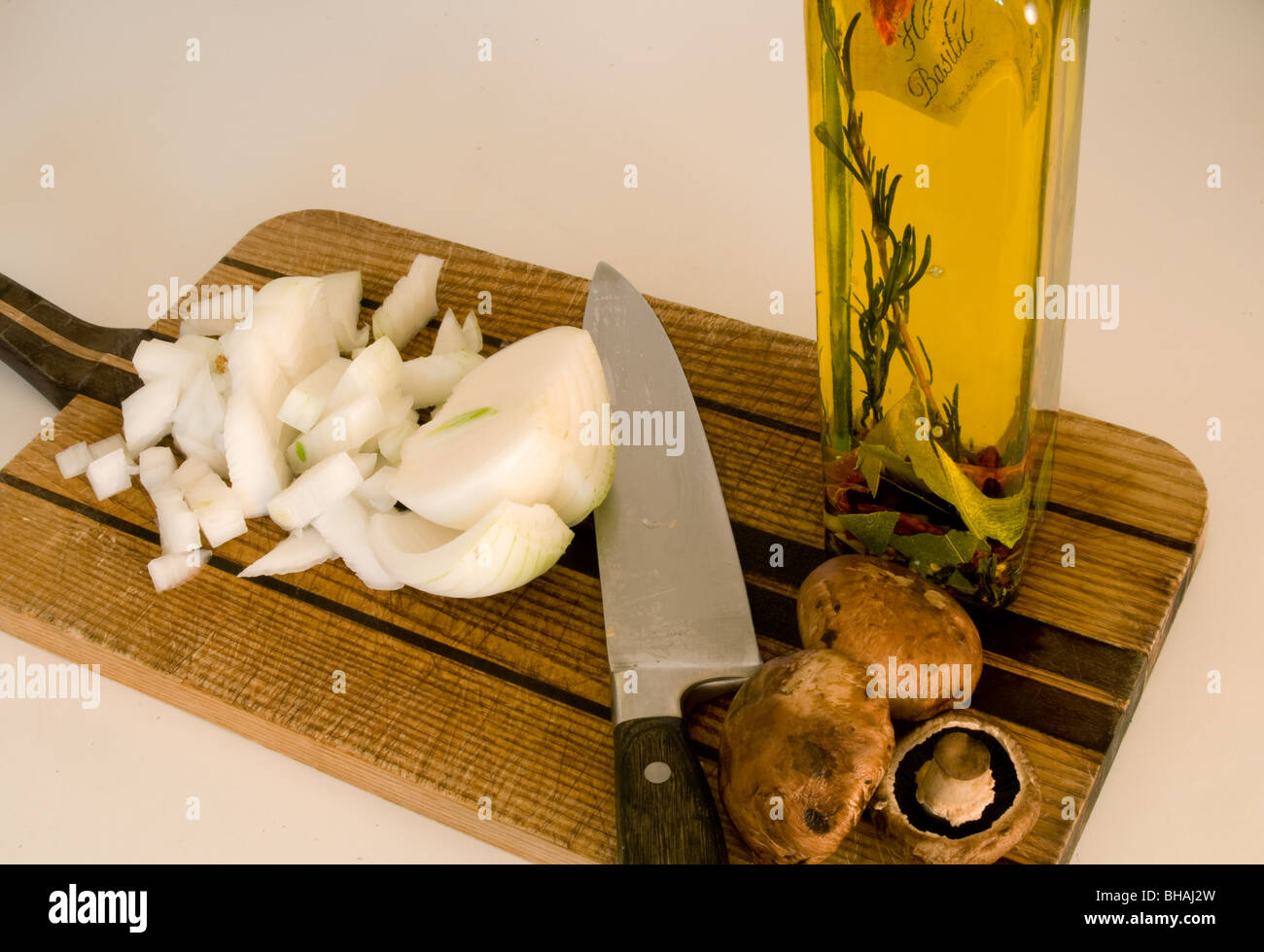 Zwiebeln, Champignons und Olivenöl auf ein Schneidebrett mit einem Messer Stockfoto