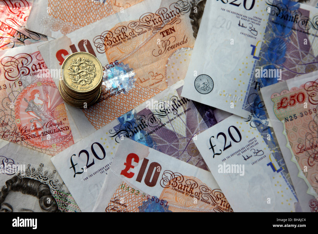 Stapel von 1 Pfund-Münzen auf Hintergrund von 50, 20 und zehn-Pfund-Noten. Stockfoto