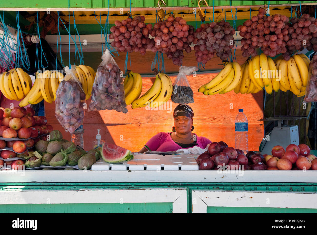 Obst-Verkäufer hinter der Theke am Markttag mit Äpfeln und tropischen Früchten auf Tobago Karibik anzeigen Stockfoto