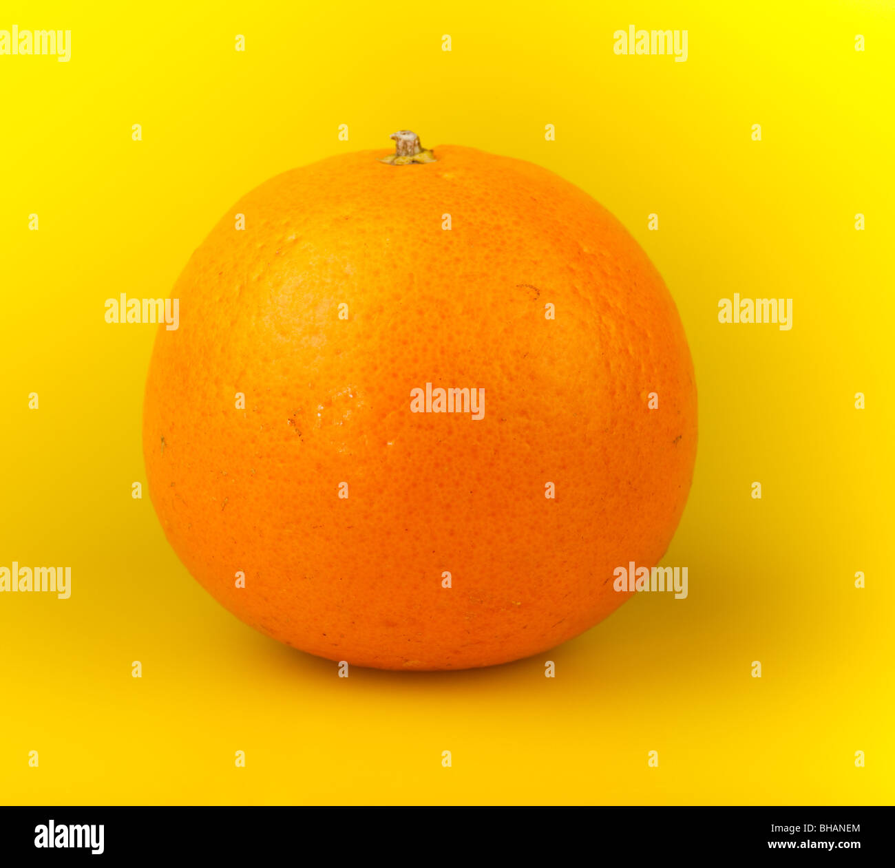 Eine Orange Mandarine auf einem gelben Hintergrund. Stockfoto
