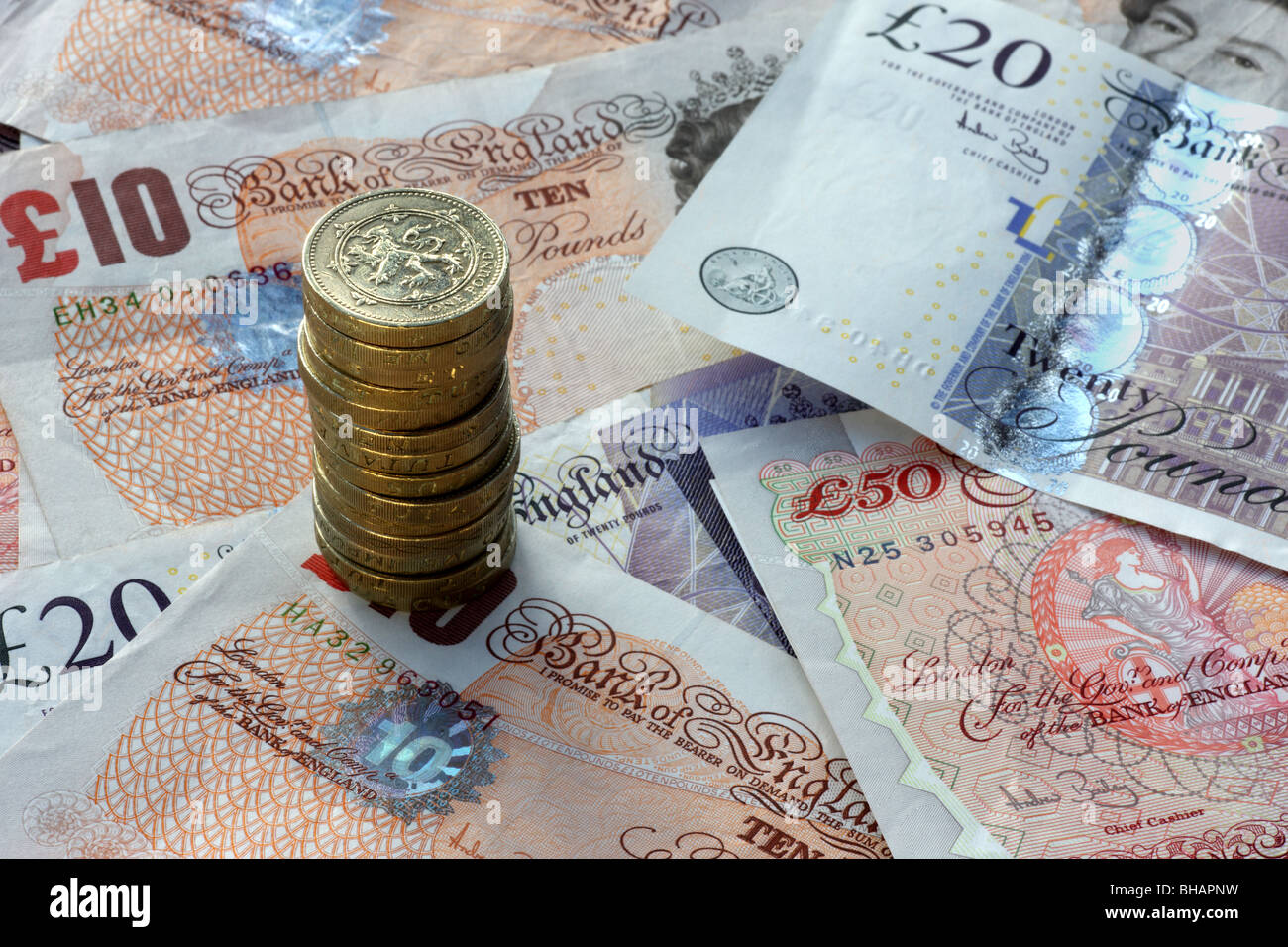 Haufen von einem Pfund Münzen vor dem Hintergrund der britischen Banknoten, 50, 20 und 10 Pfund-Noten, in der Nähe auf. Stockfoto