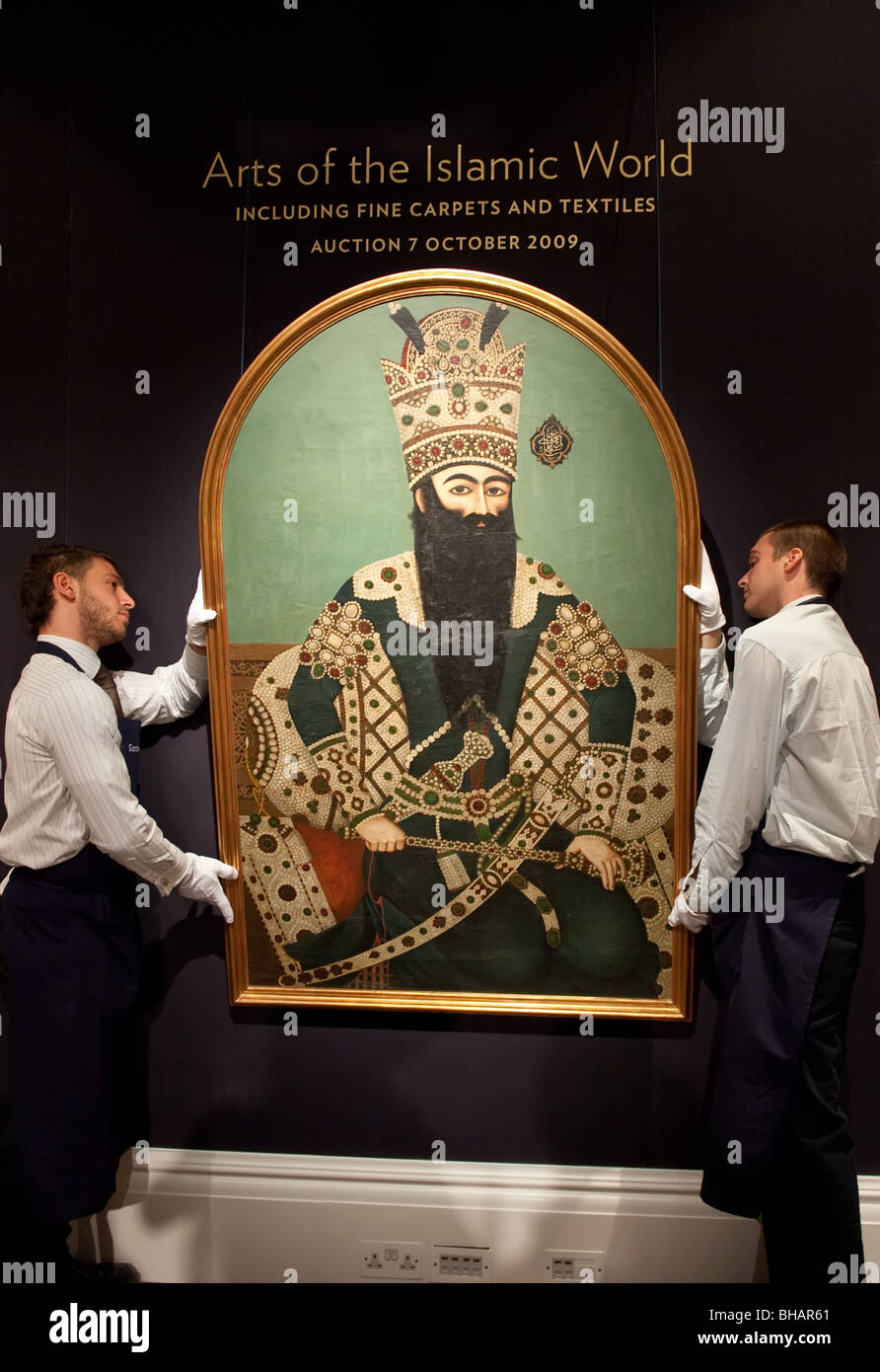Zwei Mitarbeiter tragen ein Porträt von Fath Ali Shah Qajar Bestandteil der Kunst der islamischen Welt Verkauf bei Sotheby's London Stockfoto