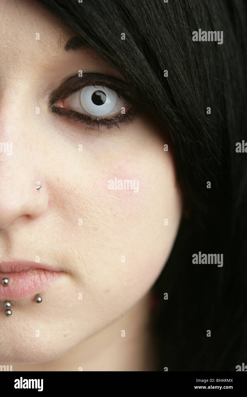 Nahaufnahme eines achtzehnjährigen Mädchen Gesichts zeigen farbige Kontaktlinsen und Lippenpiercings. Stockfoto