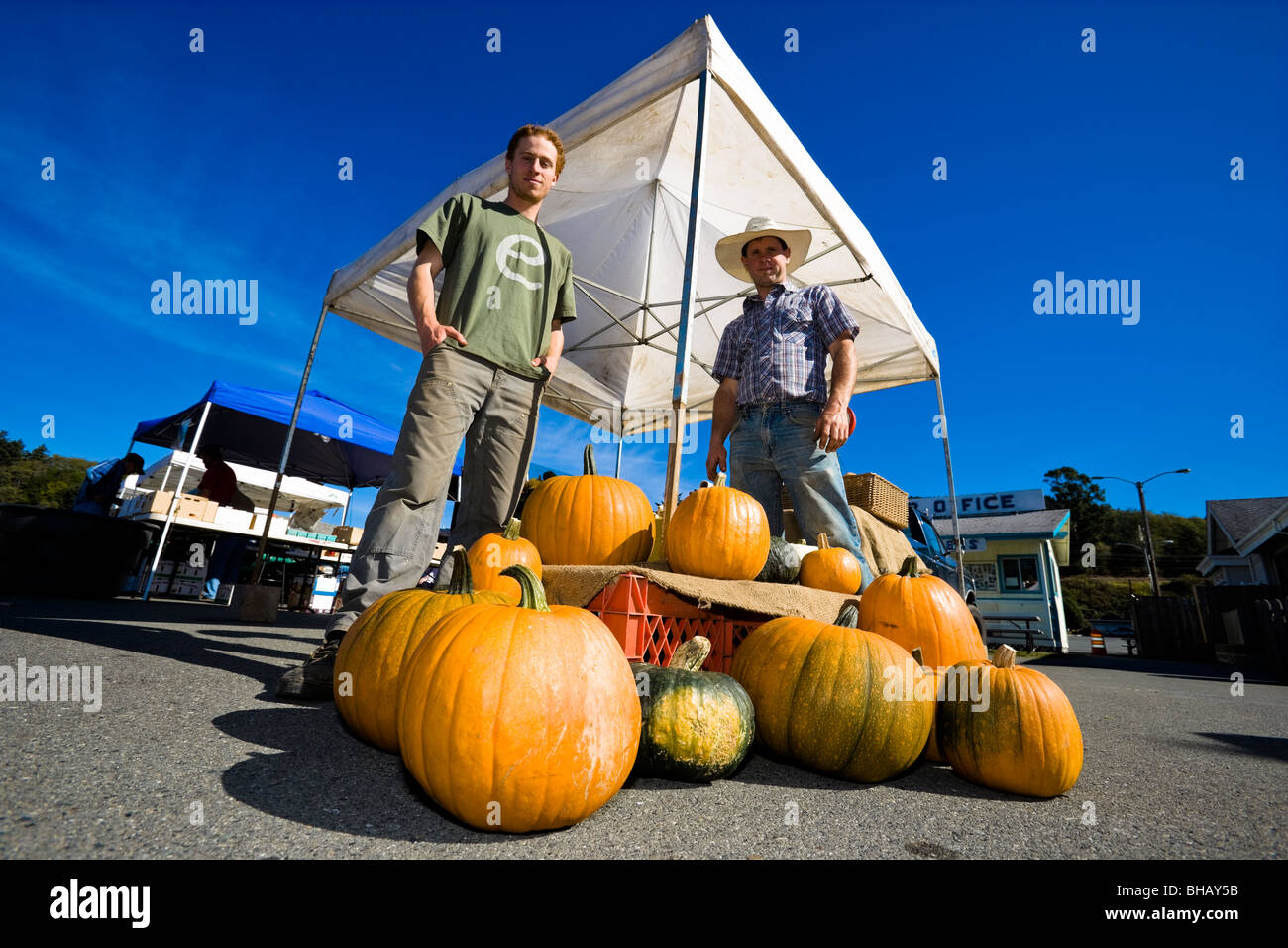 Große Kürbisse zum Verkauf mit Anbietern stehen neben ihnen auf dem Bauernmarkt Brookings, Brookings, Oregon, USA Stockfoto