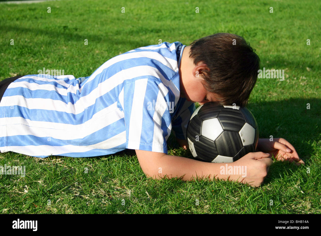 Junge Fußballer mit seinem Kopf auf Kugel verärgert mit dem Spiel Stockfoto