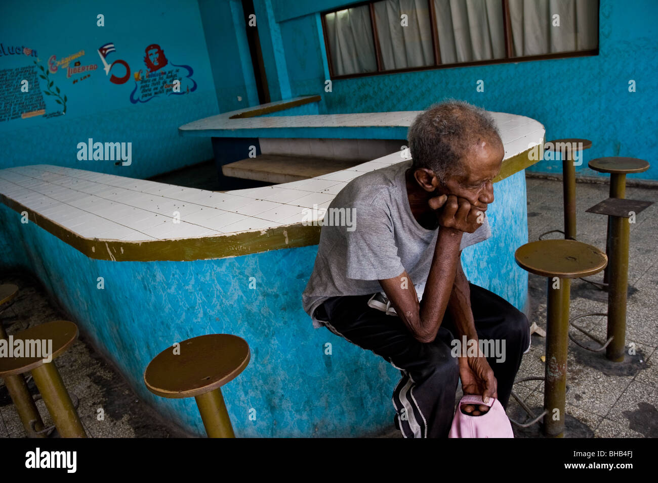 Eine alte kubanische Mann sitzen an einem leeren Lunch Counter in Santa Clara, Kuba. Stockfoto