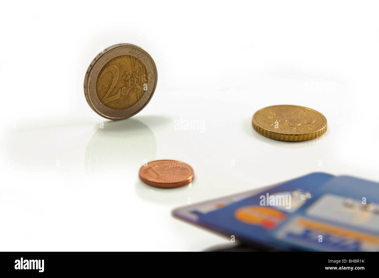 Konzeptionelle Bild zur Veranschaulichung von Wettbewerb e-Geld gegen Bargeld. Fokus auf 2 Euro Münze. Flache Freiheitsgrad. Weißer Hintergrund. Stockfoto