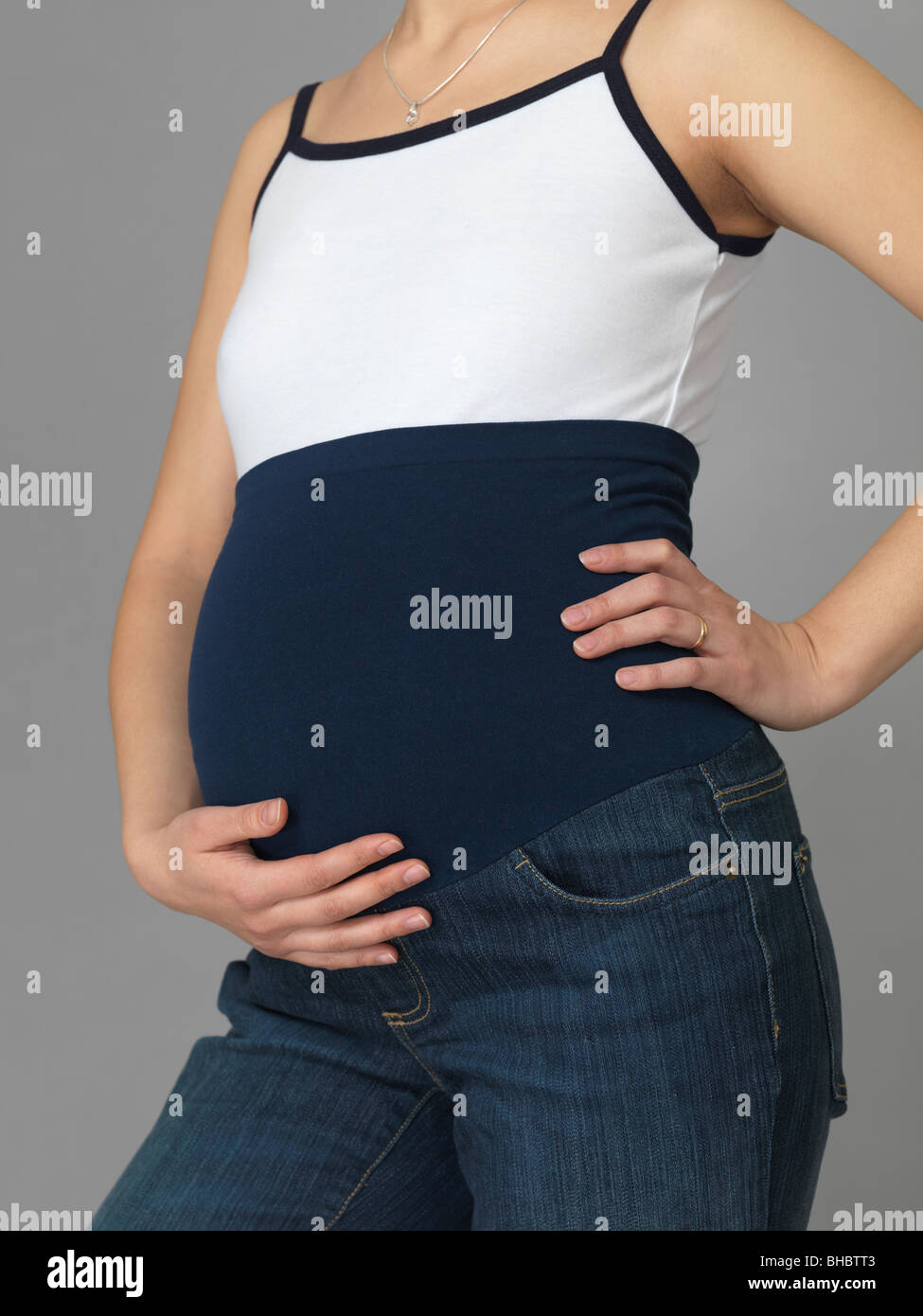 Schwangere junge Frau trägt Umstandsjeans mit einer Stretch-Band um den Bauch Stockfoto