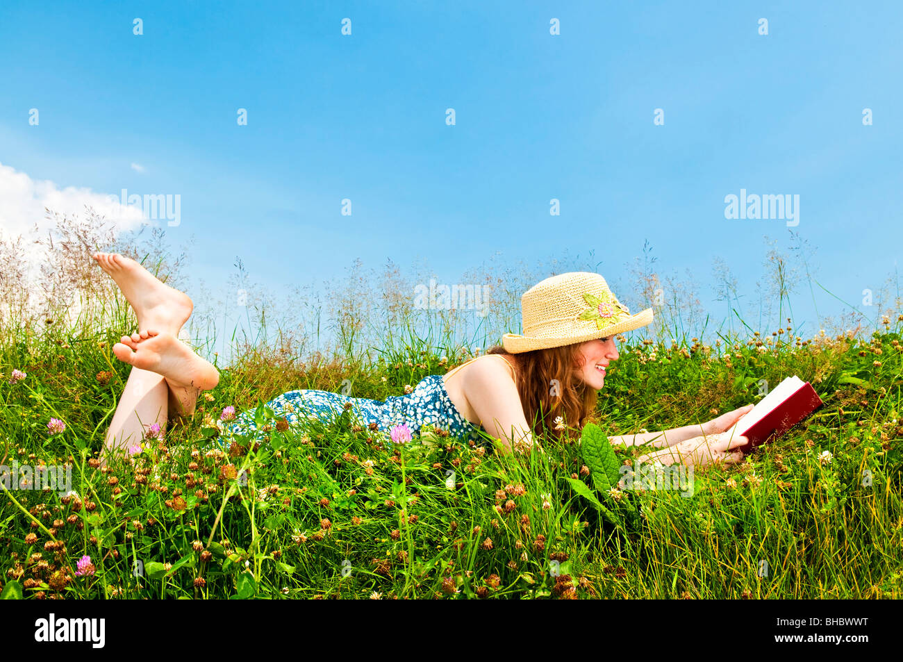Junge Teenager-Mädchen-Lesebuch in Sommerwiese mit Strohhut Stockfoto