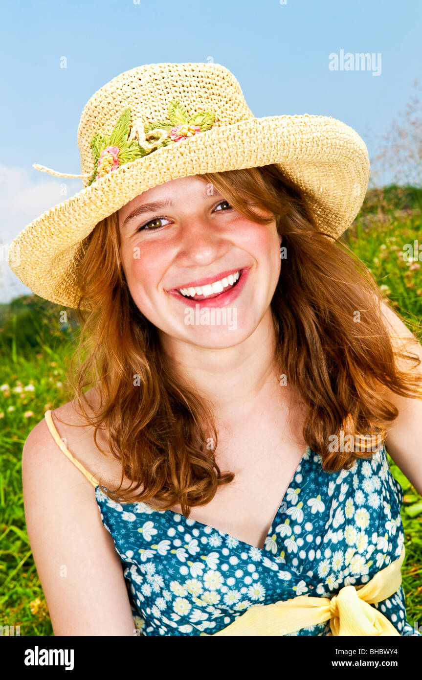 Porträt des jungen Mädchens lächelnd auf Sommerwiese im Strohhut Stockfoto