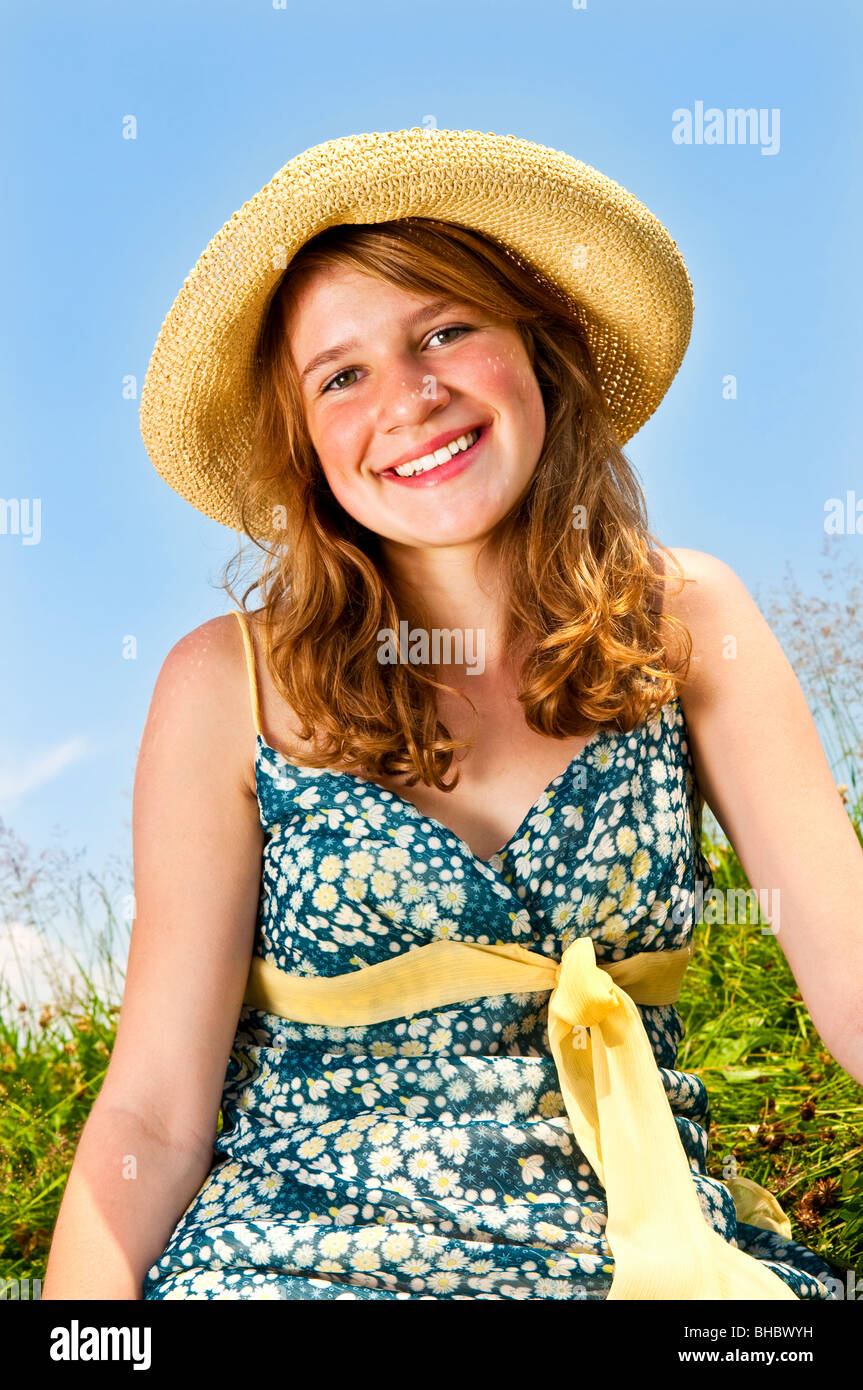 Junge Teenager-Mädchen sitzen auf Sommerwiese im Strohhut Stockfoto