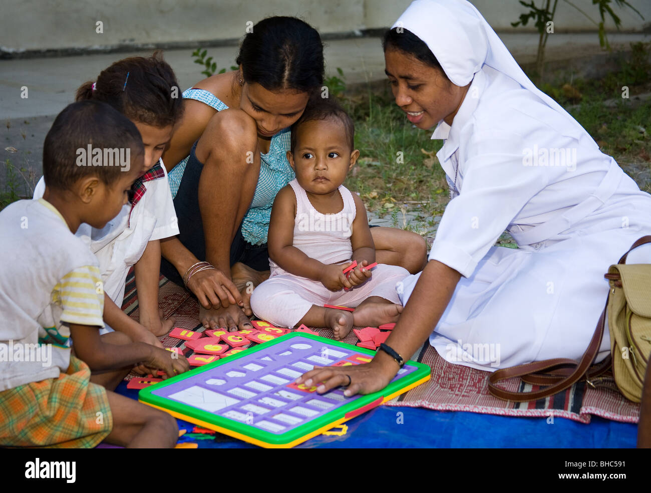 Katholische Nonne hilft Kindern Lernspiele im Flüchtlingslager in Dili Osttimor Teil des Oxfam Gesundheit und Lernprogramm Stockfoto