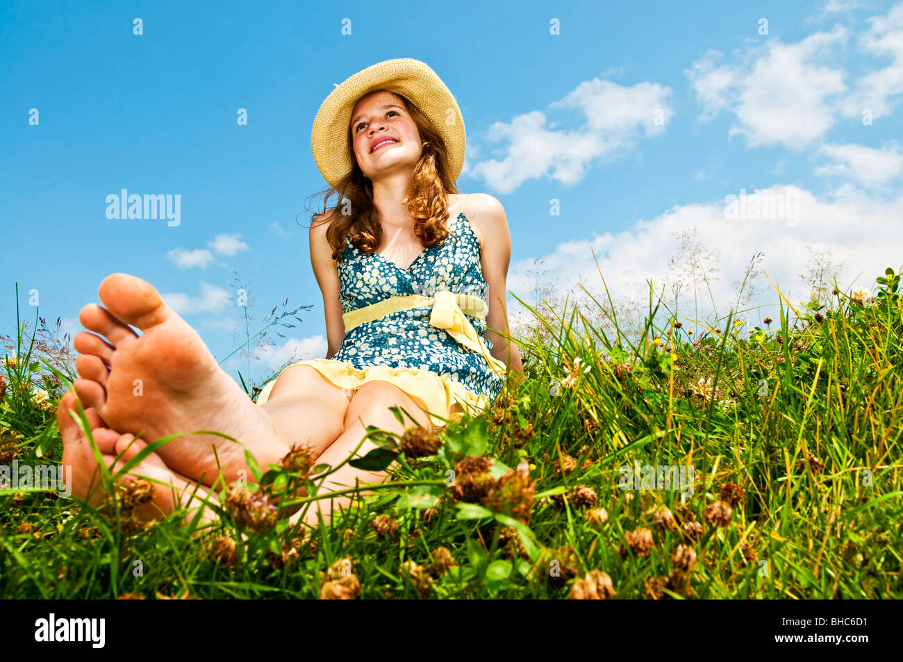 Junge TeenagerMädchen sitzen auf Sommerwiese barfuß Stockfotografie