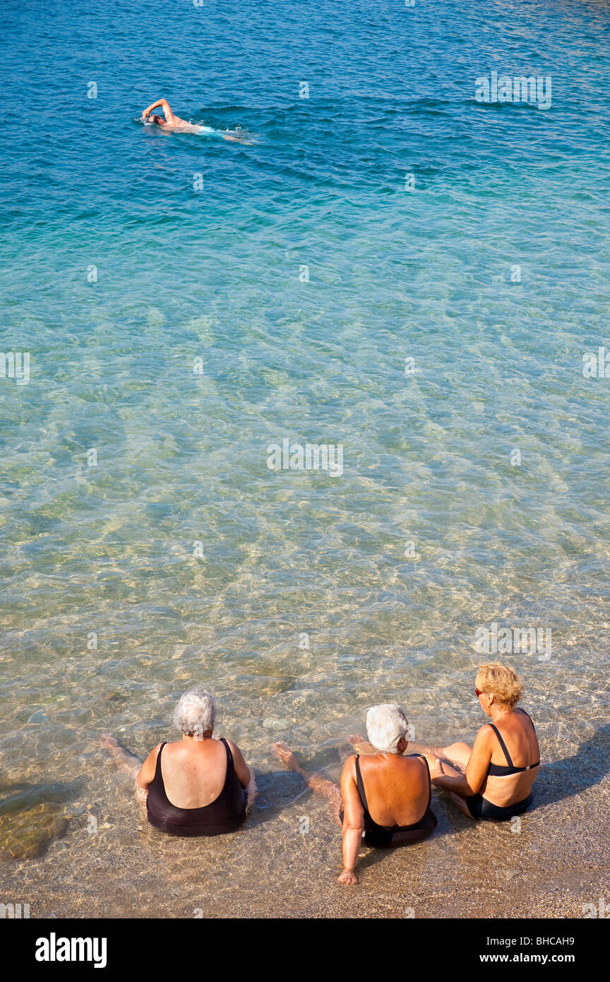 Frauen in Führungspositionen sitzen im Ozean am Strand in Italien Stockfoto