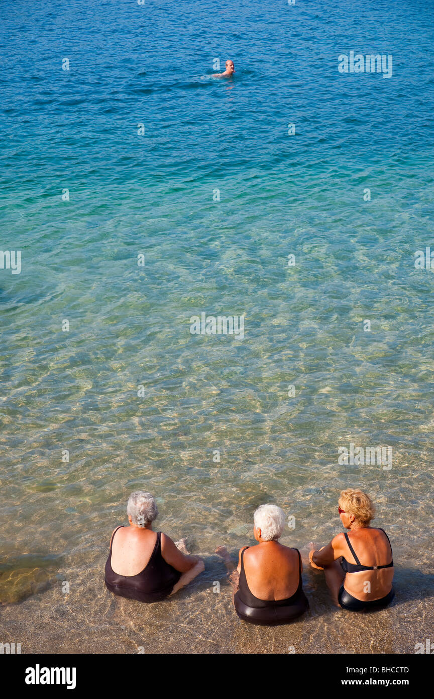 Frauen in Führungspositionen sitzen im Ozean am Strand in Italien Stockfoto