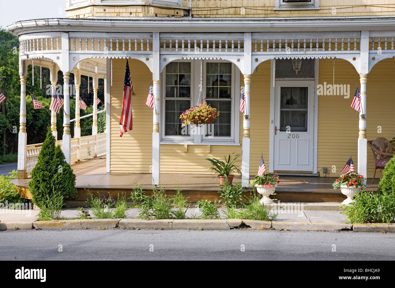 Americana klassische gelbe Veranda zeigt die amerikanische Flagge in Lancaster County, Pennsylvania Stockfoto