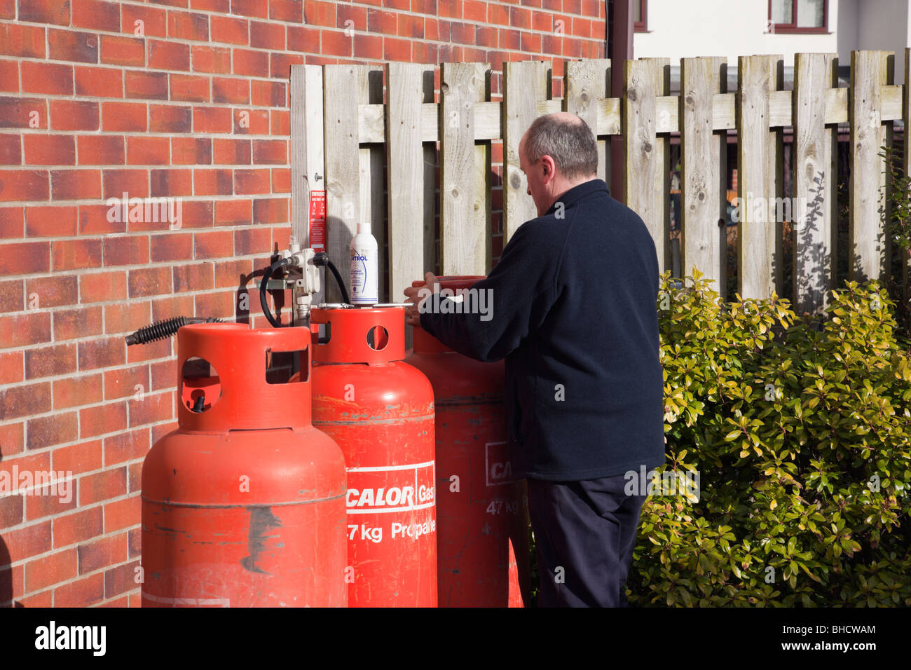 UK, Großbritannien. Arbeiter eine inländischen Calor Gasflasche vor einem Haus ändern Stockfoto