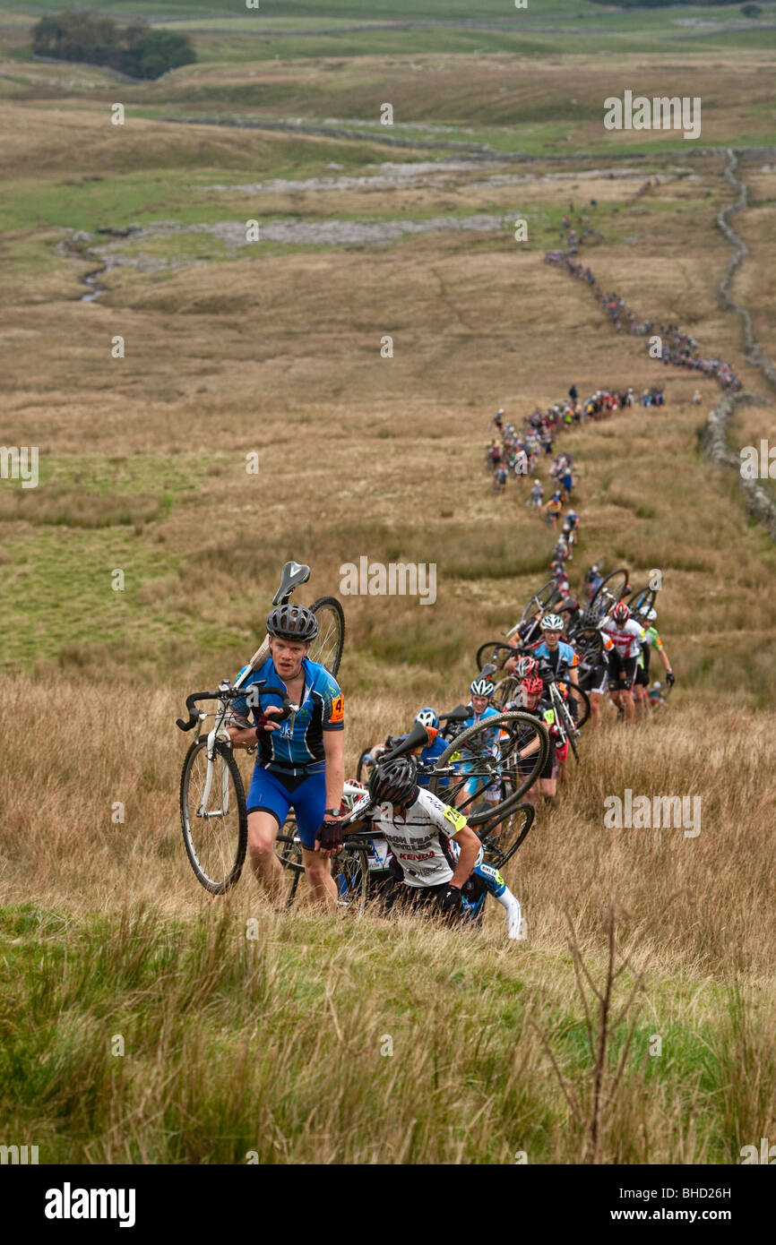 Masse der Radfahrer tragen ihre Fahrräder auf einem Berg während der drei Zinnen Cyclo-Cross in Yorkshire, Vereinigtes Königreich Stockfoto