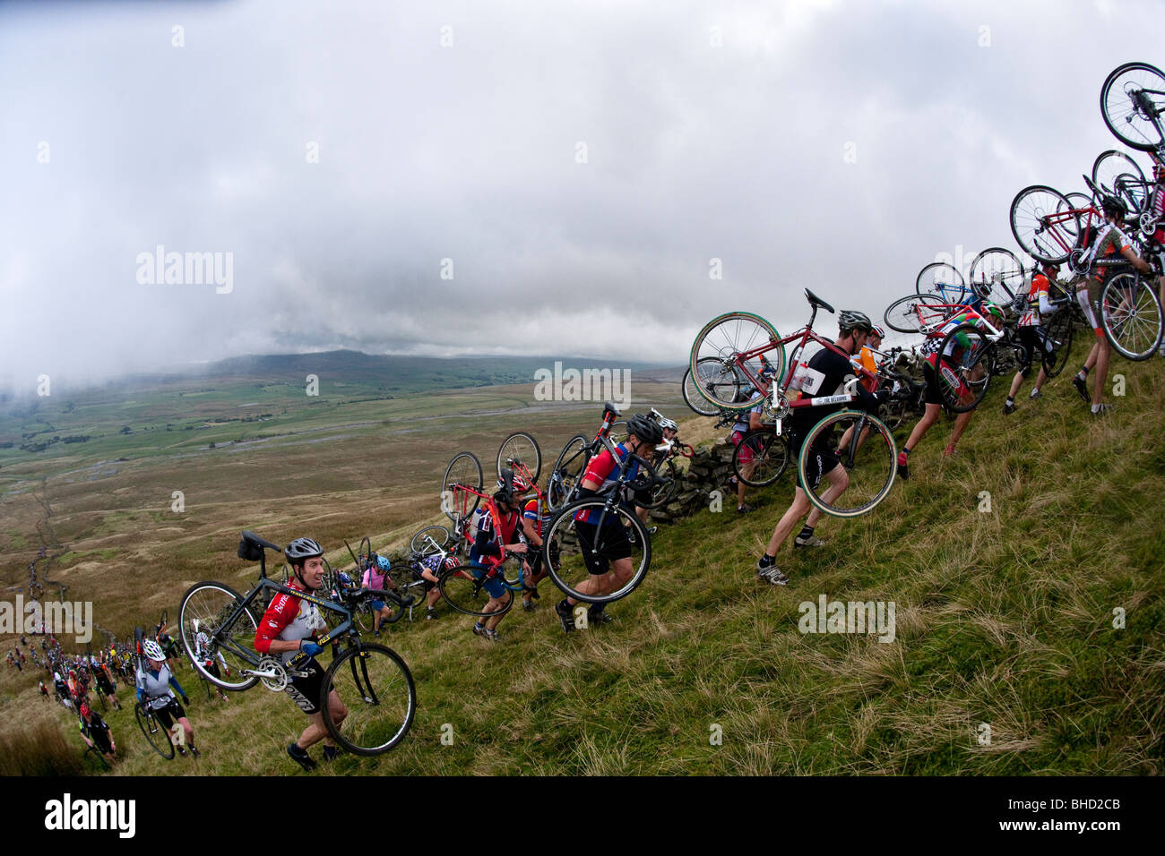 Masse der Radfahrer tragen ihre Fahrräder auf einem Berg während der drei Zinnen Cyclo-Cross in Yorkshire, Vereinigtes Königreich Stockfoto