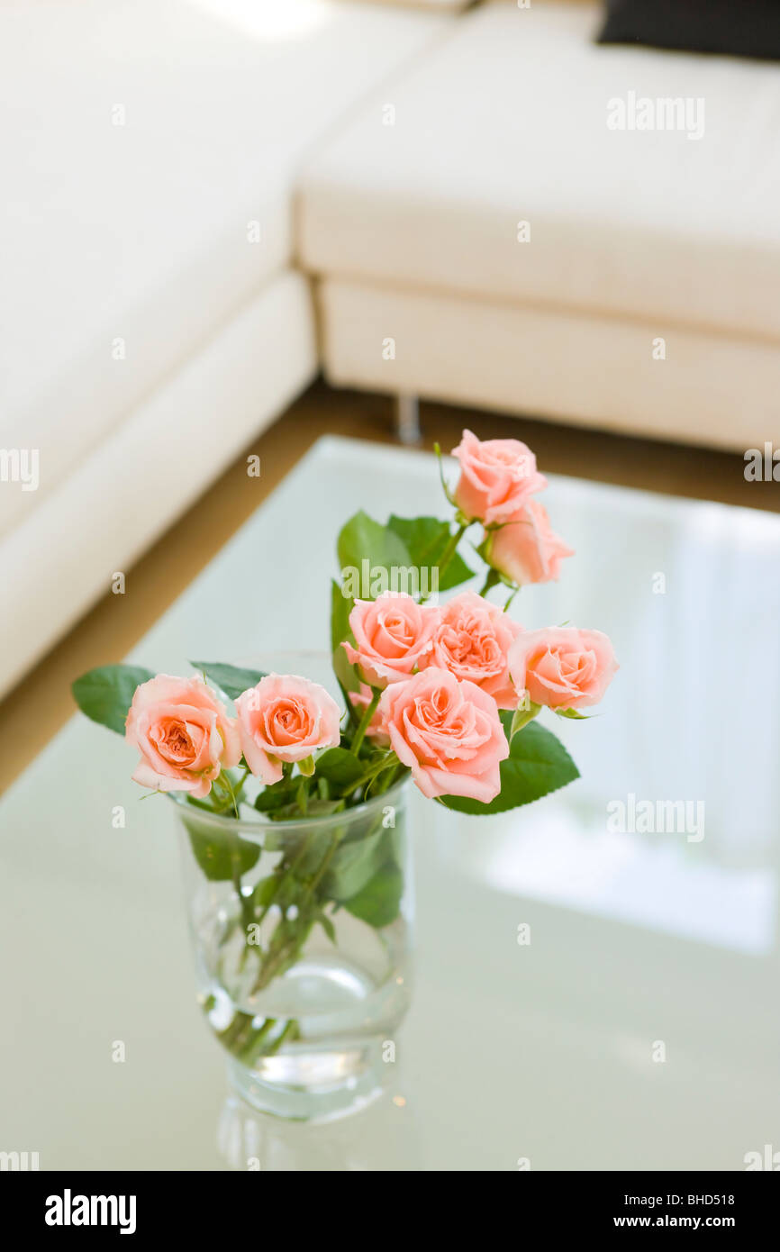 Vase mit Rosen auf Tisch im Wohnzimmer. Stockfoto