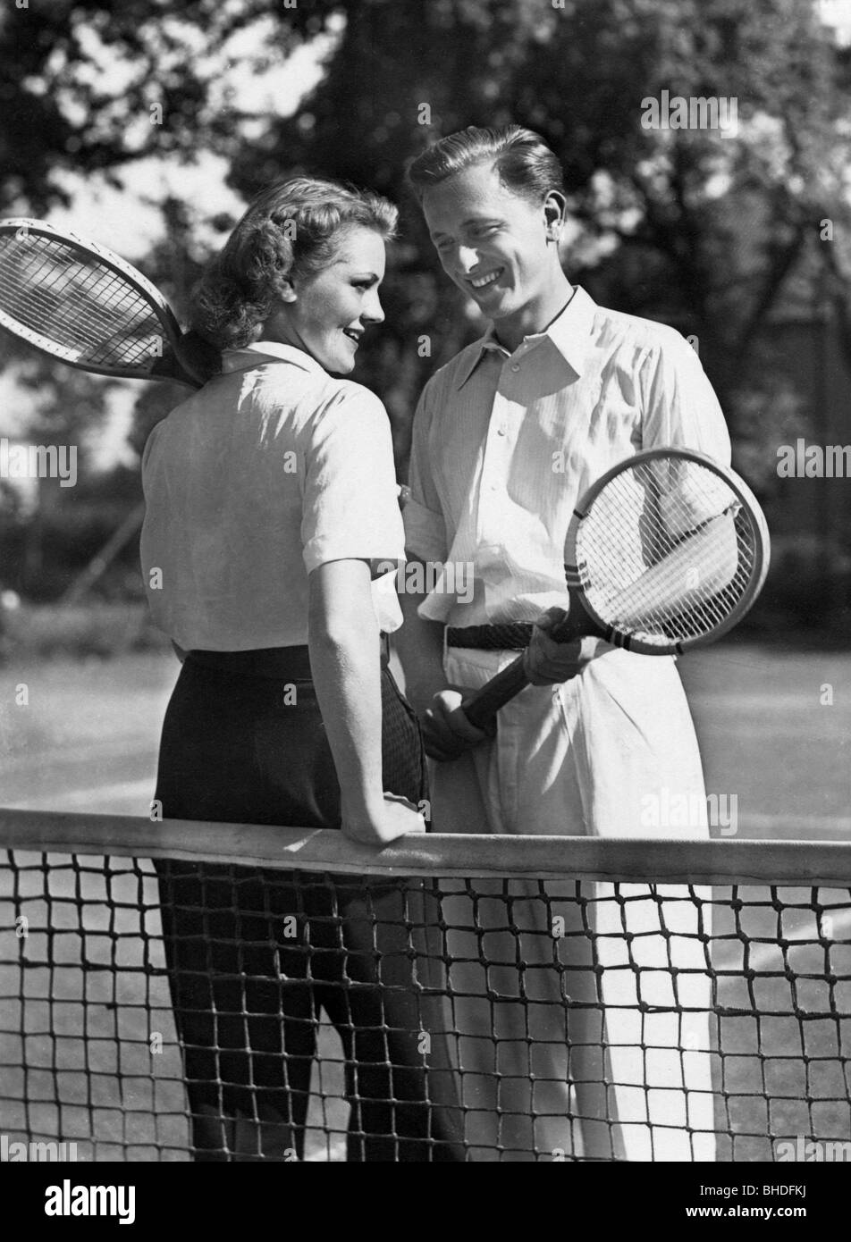 Sport, Tennis, junges Paar mit Tennisschlägern im Netz, 1930er Jahre, Postkarte, Stockfoto