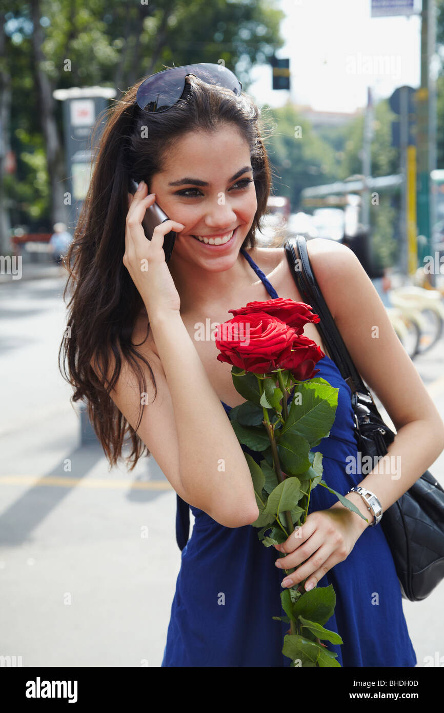 Brasilianische Frau halten rote Rosen und reden über Handy Stockfoto
