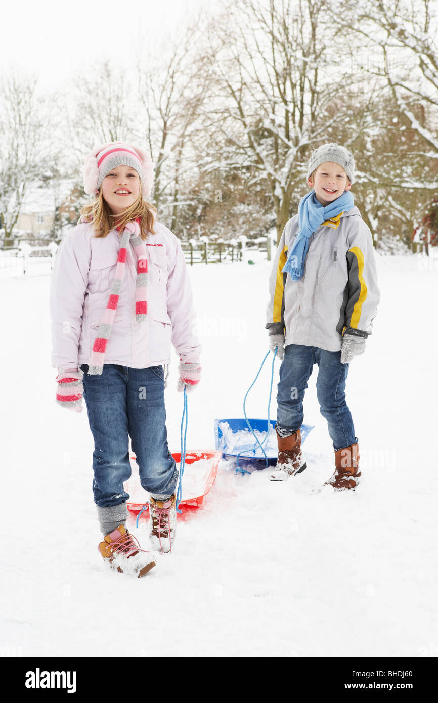 Kinder ziehen Schlitten durch tief verschneite Landschaft Stockfoto